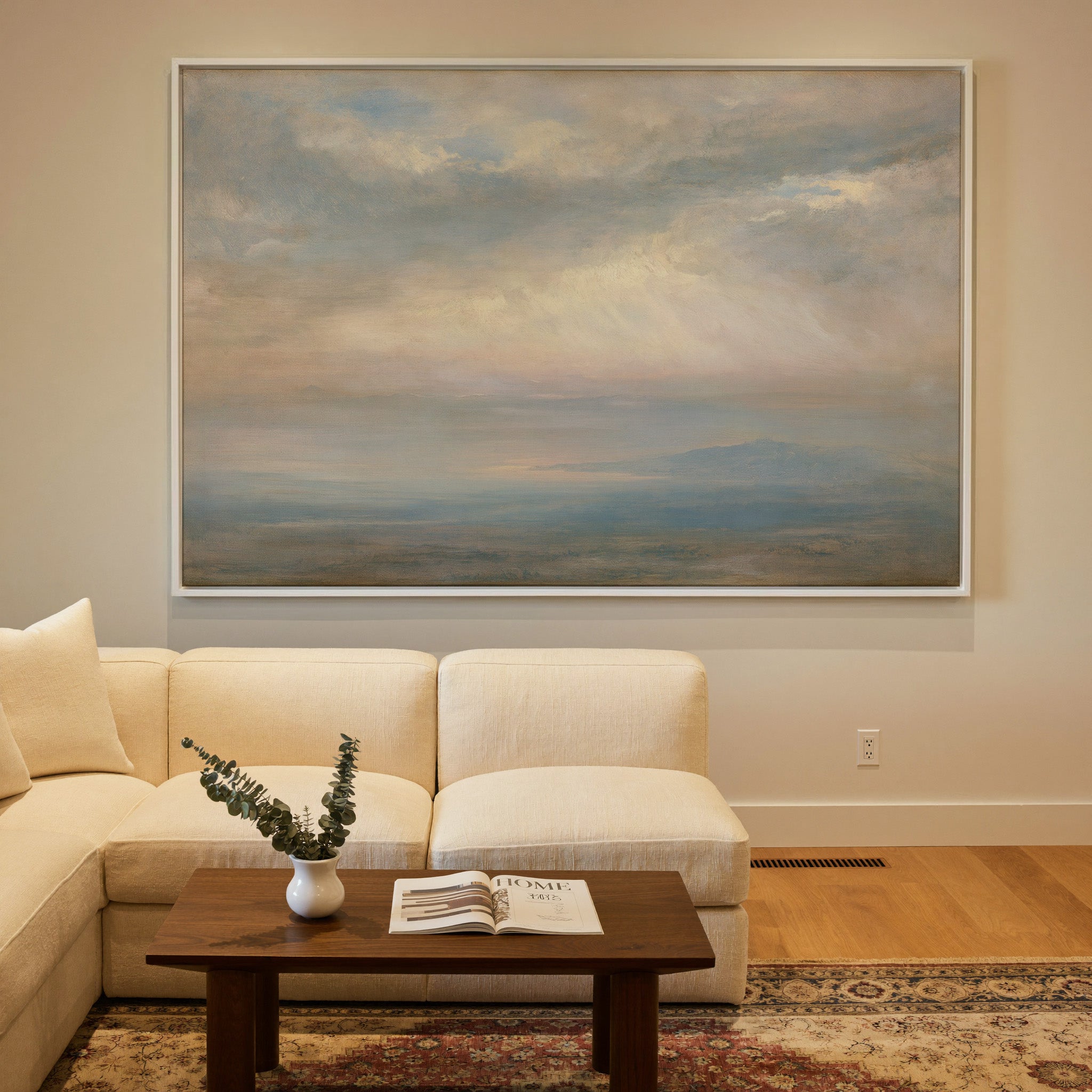 pale cloudscape with sea mist and a low distant canvas wall art in a white frame in a styled room setting