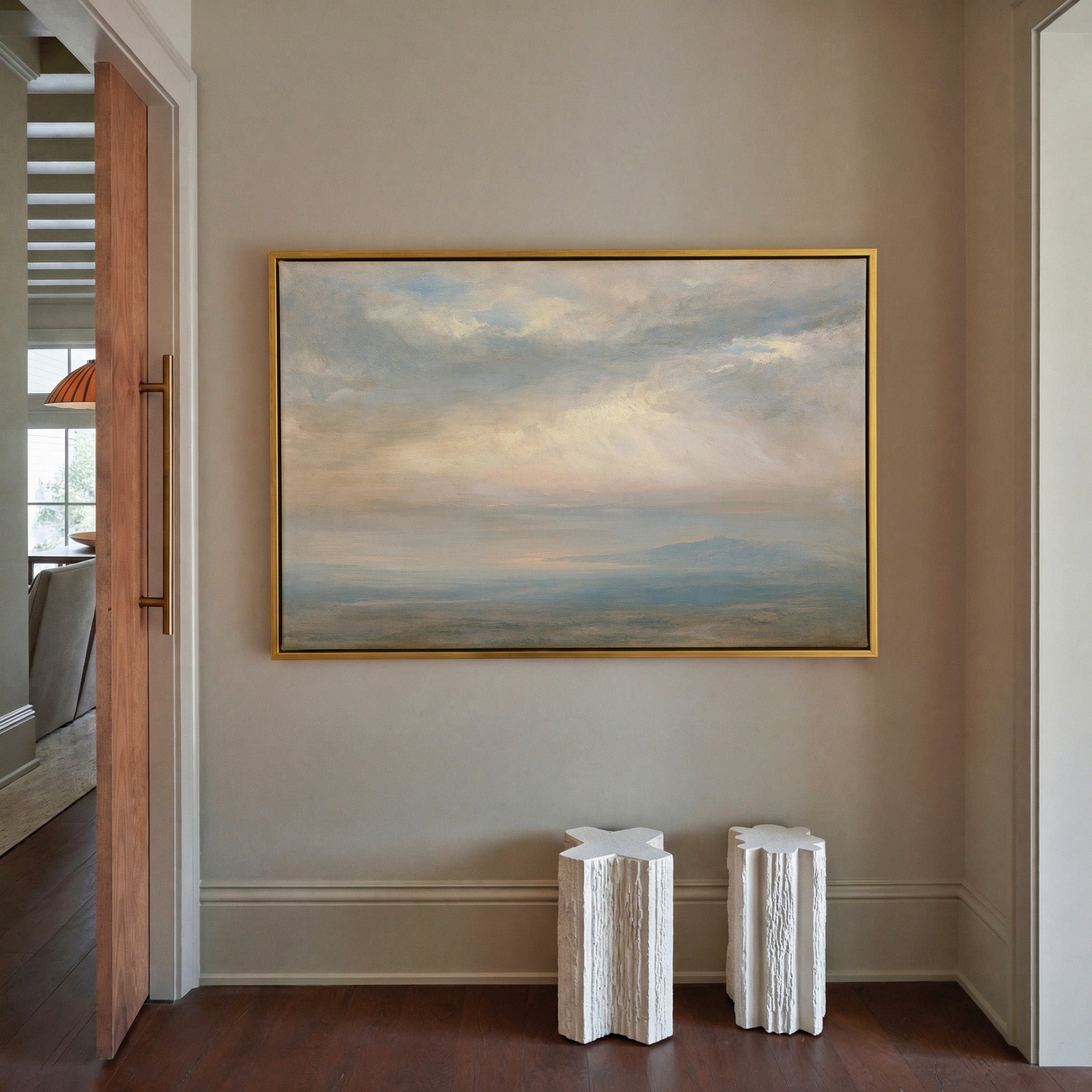pale cloudscape with sea mist and a low distant canvas wall art in a gold frame in a styled room setting