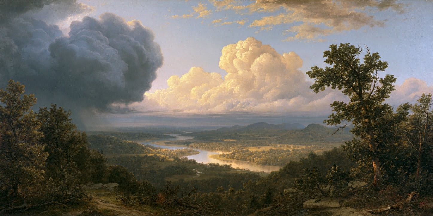 Wide river valley with bright clouds overhead and wooded hills framing the foreground