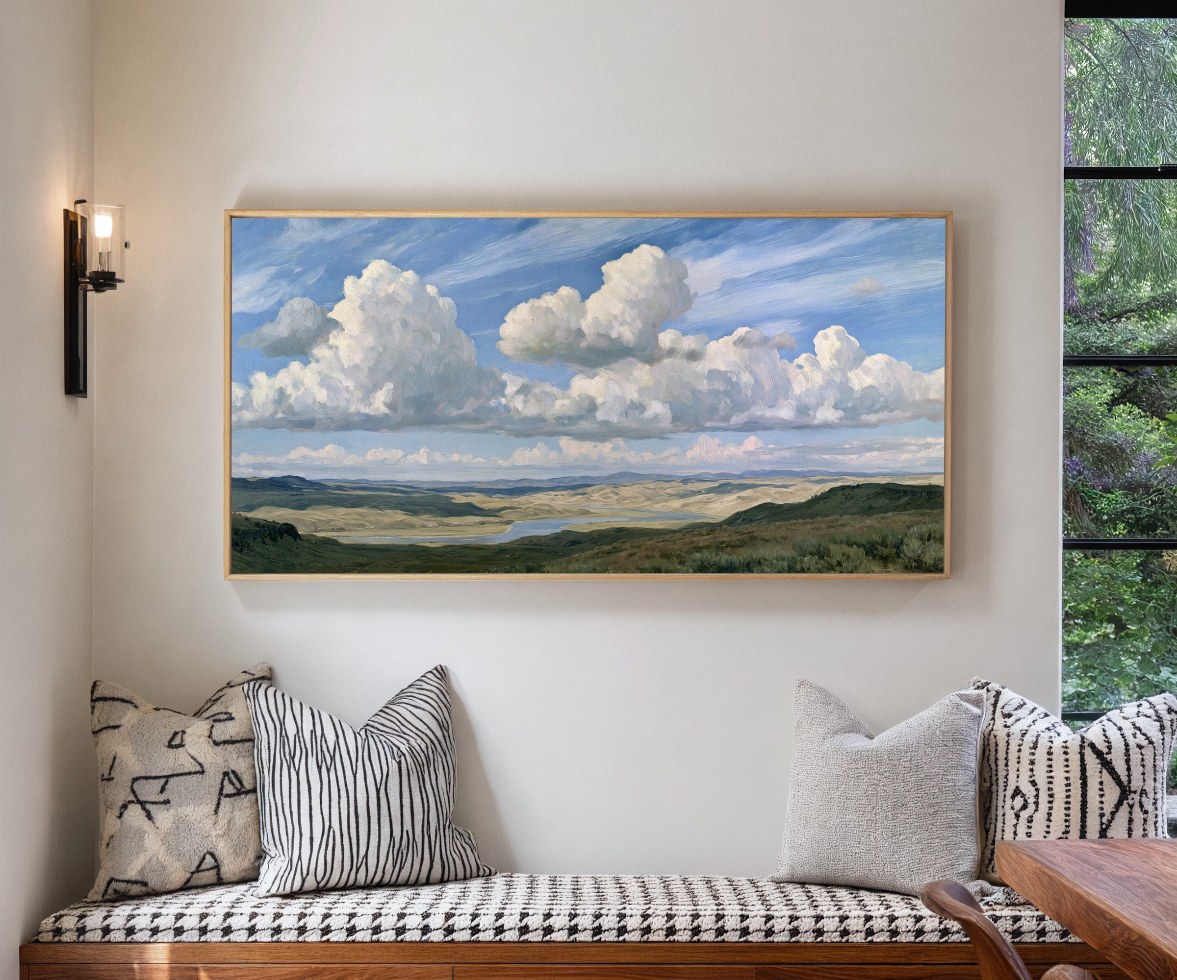 blue sky with towering white cloud banks over a canvas wall art in a natural wood frame in a living room