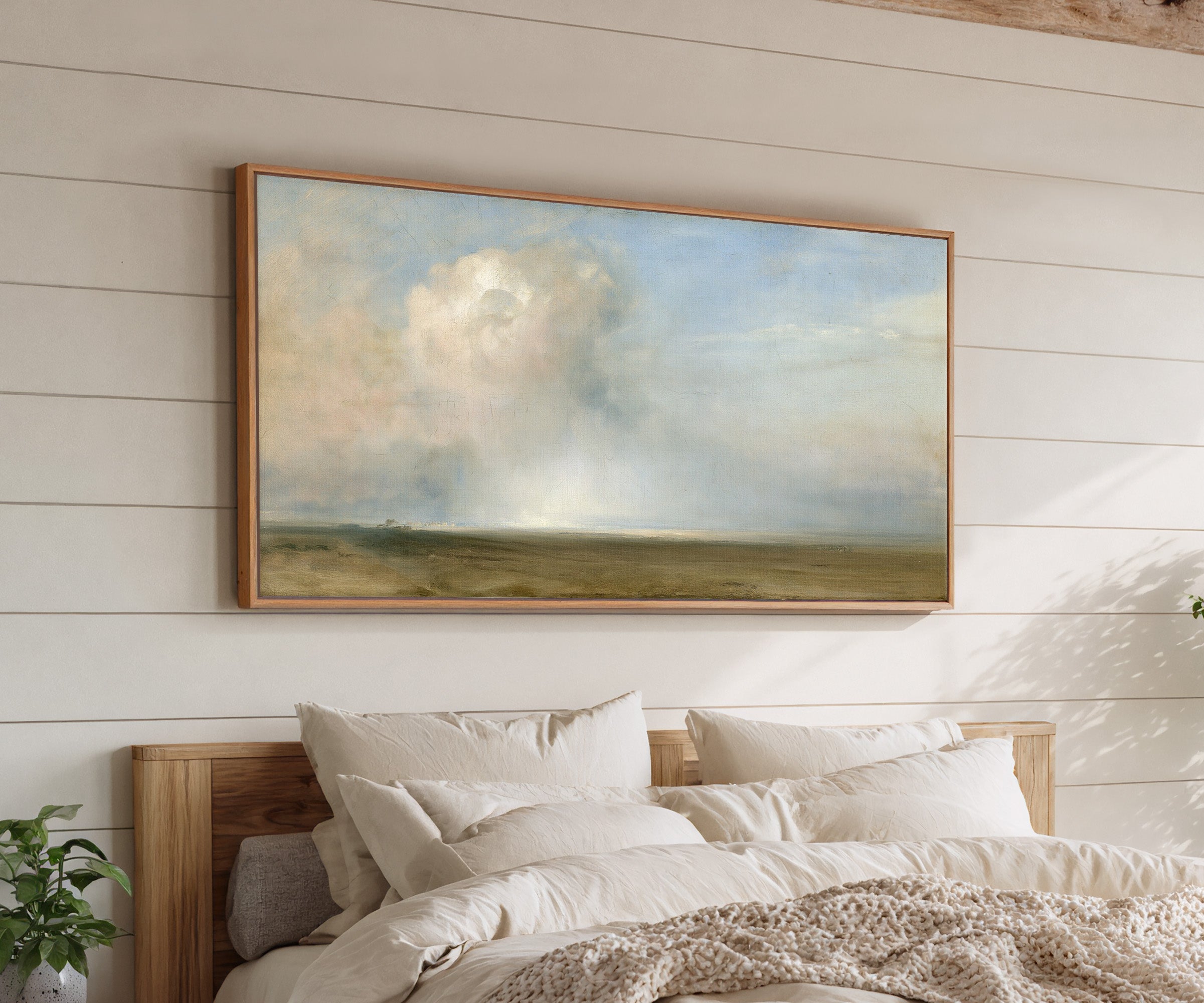 single towering cumulus cloud over a low plain canvas wall art in an oak frame above a bed