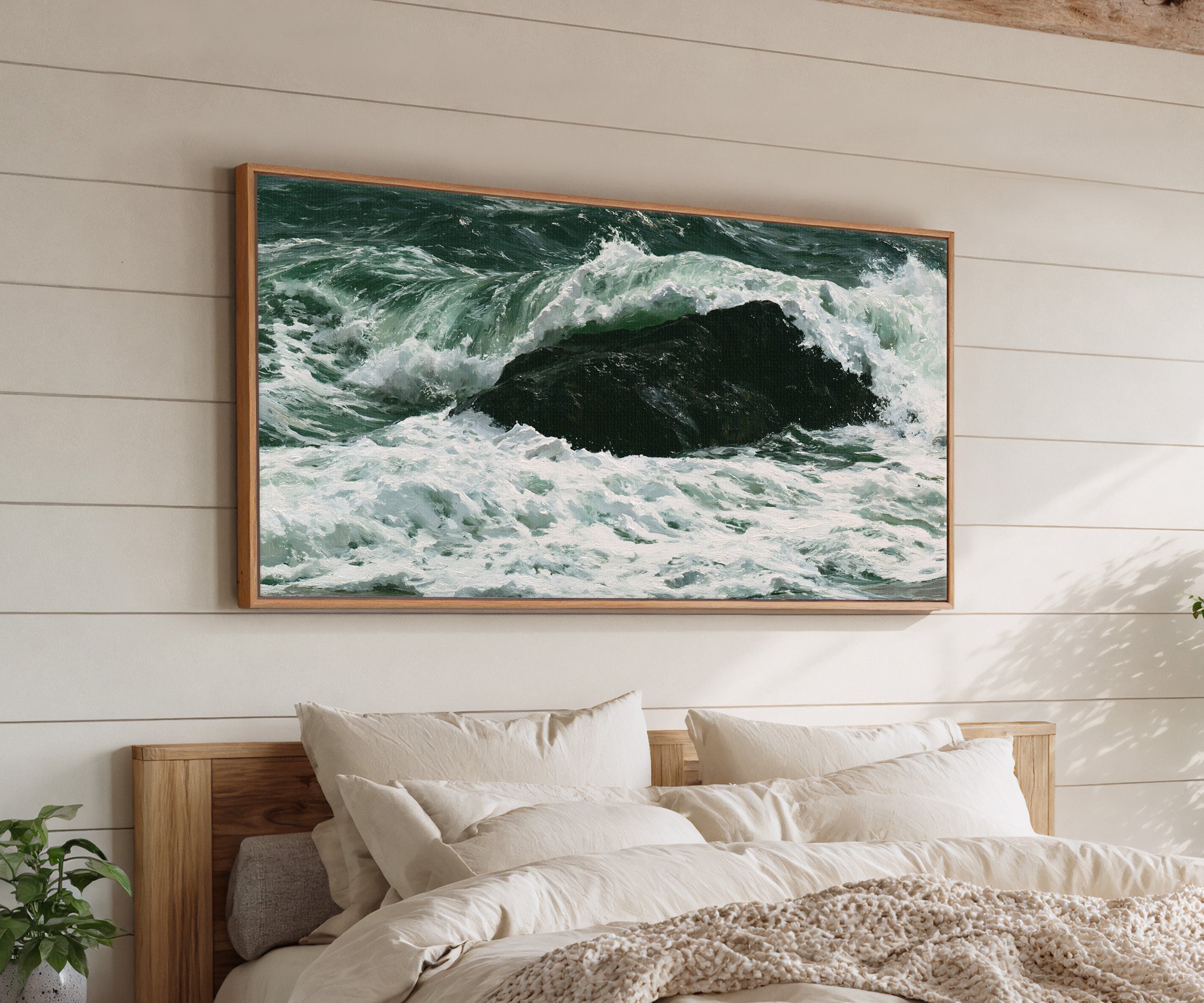 dark atlantic wave breaking over black rock canvas wall art in an oak frame above a bed