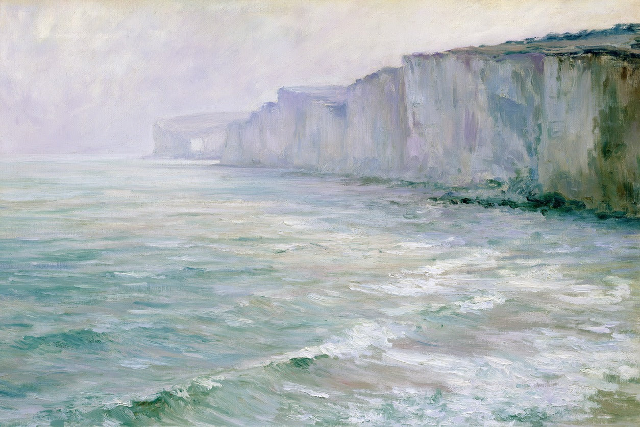 Chalk cliffs above pale green sea, with thin surf and a hazy headland receding left