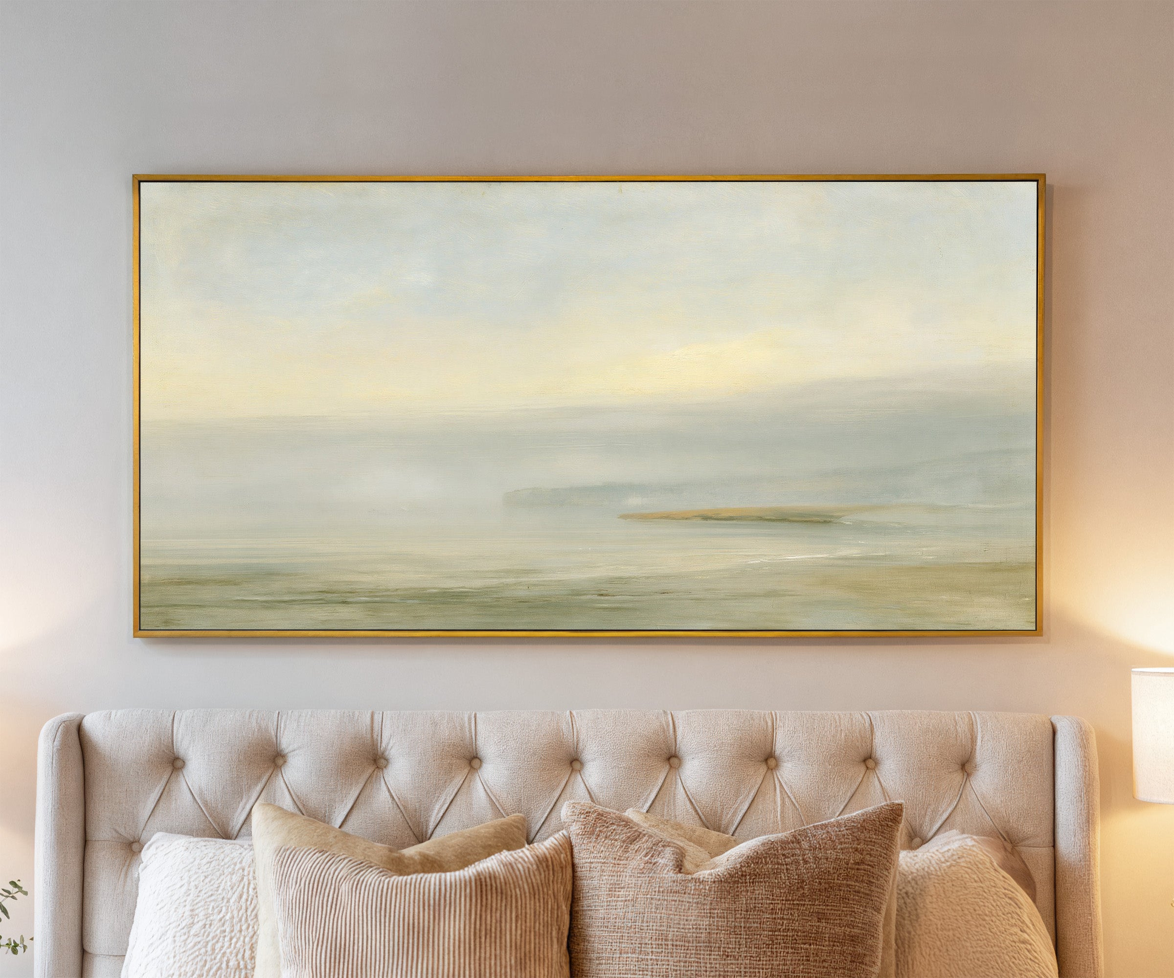 pale sea with a faint distant headland canvas wall art in a gold frame above a bed