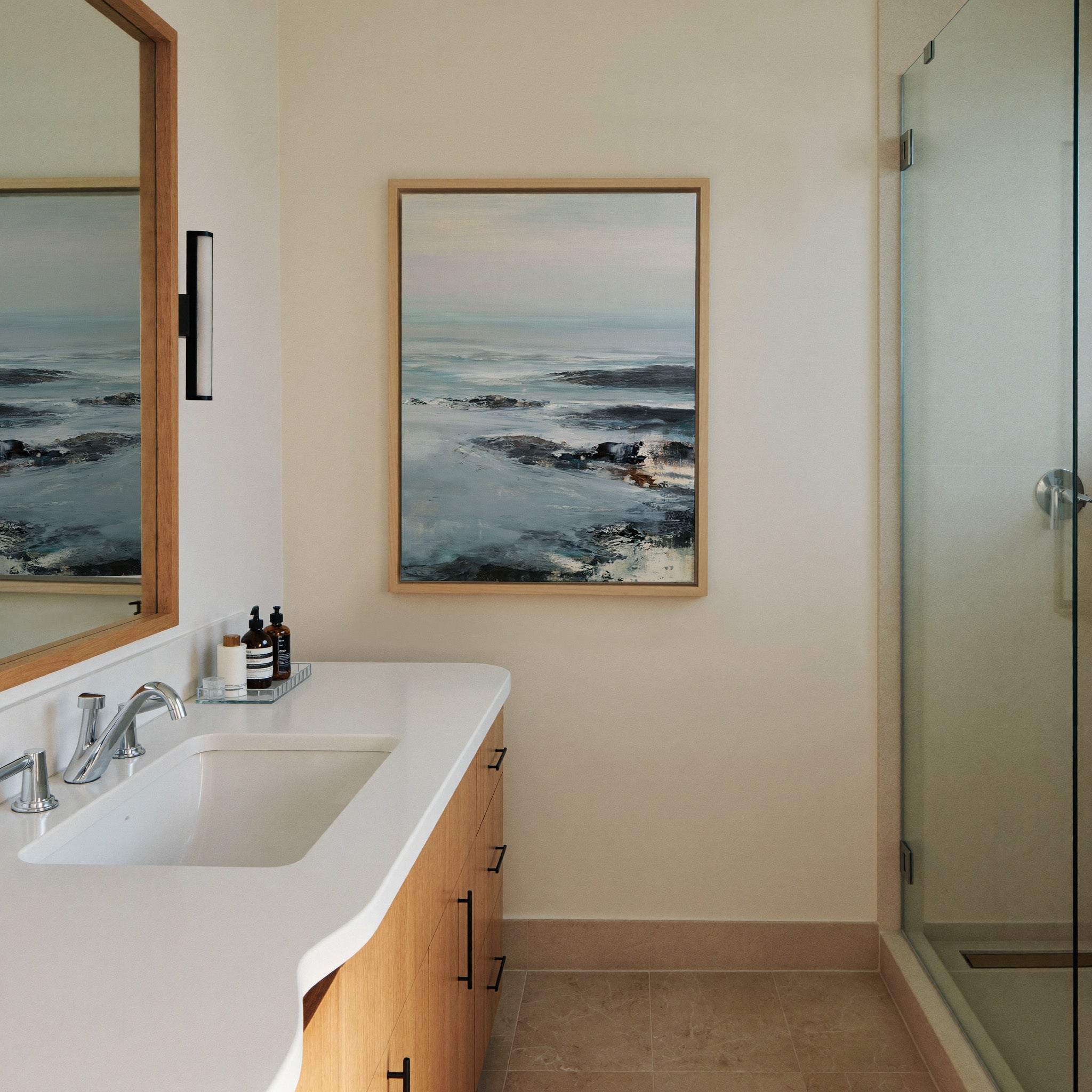 cold northern sea with pale sky and dark rock canvas wall art in a natural wood frame in a styled room setting