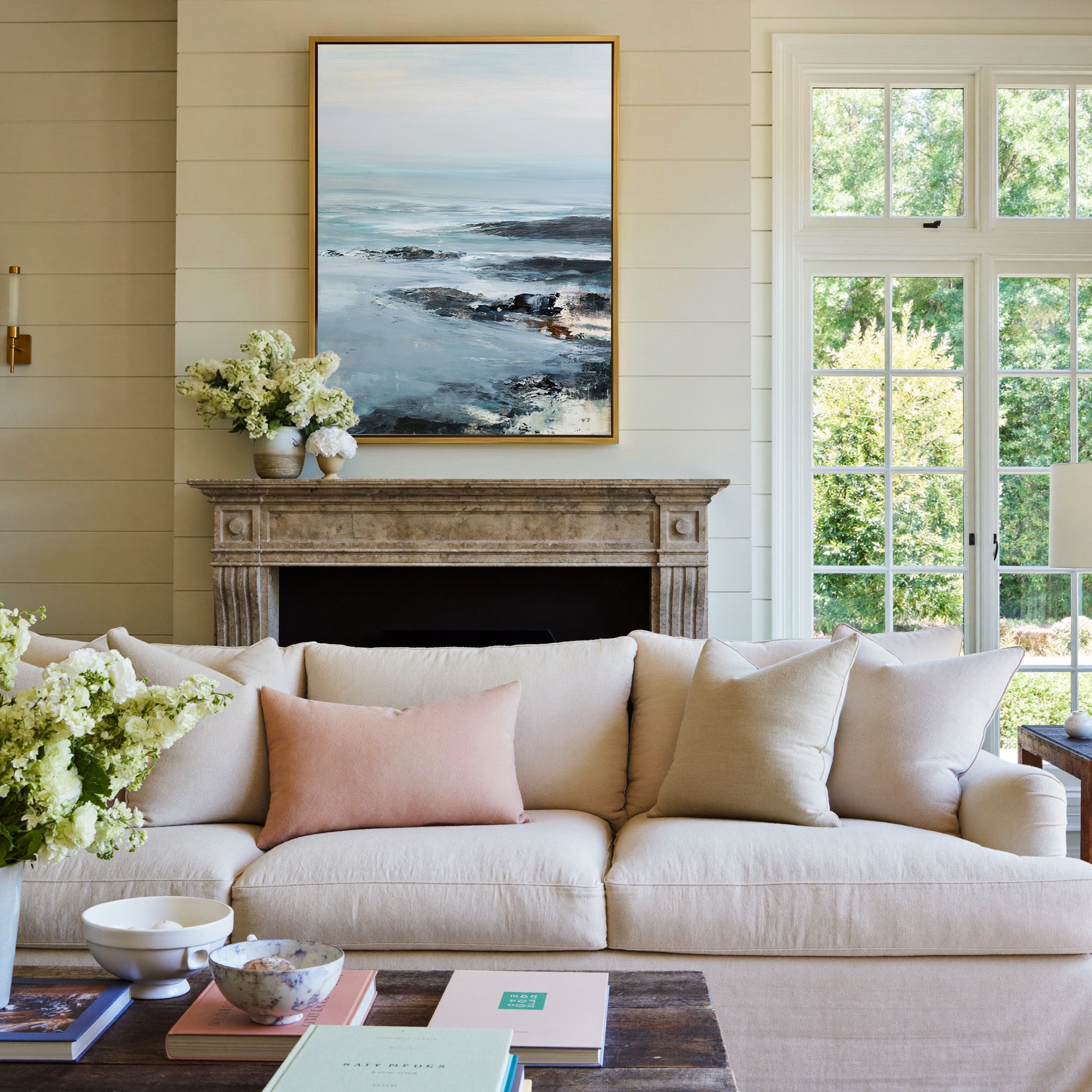 cold northern sea with pale sky and dark rock canvas wall art in a gold frame above a mantel