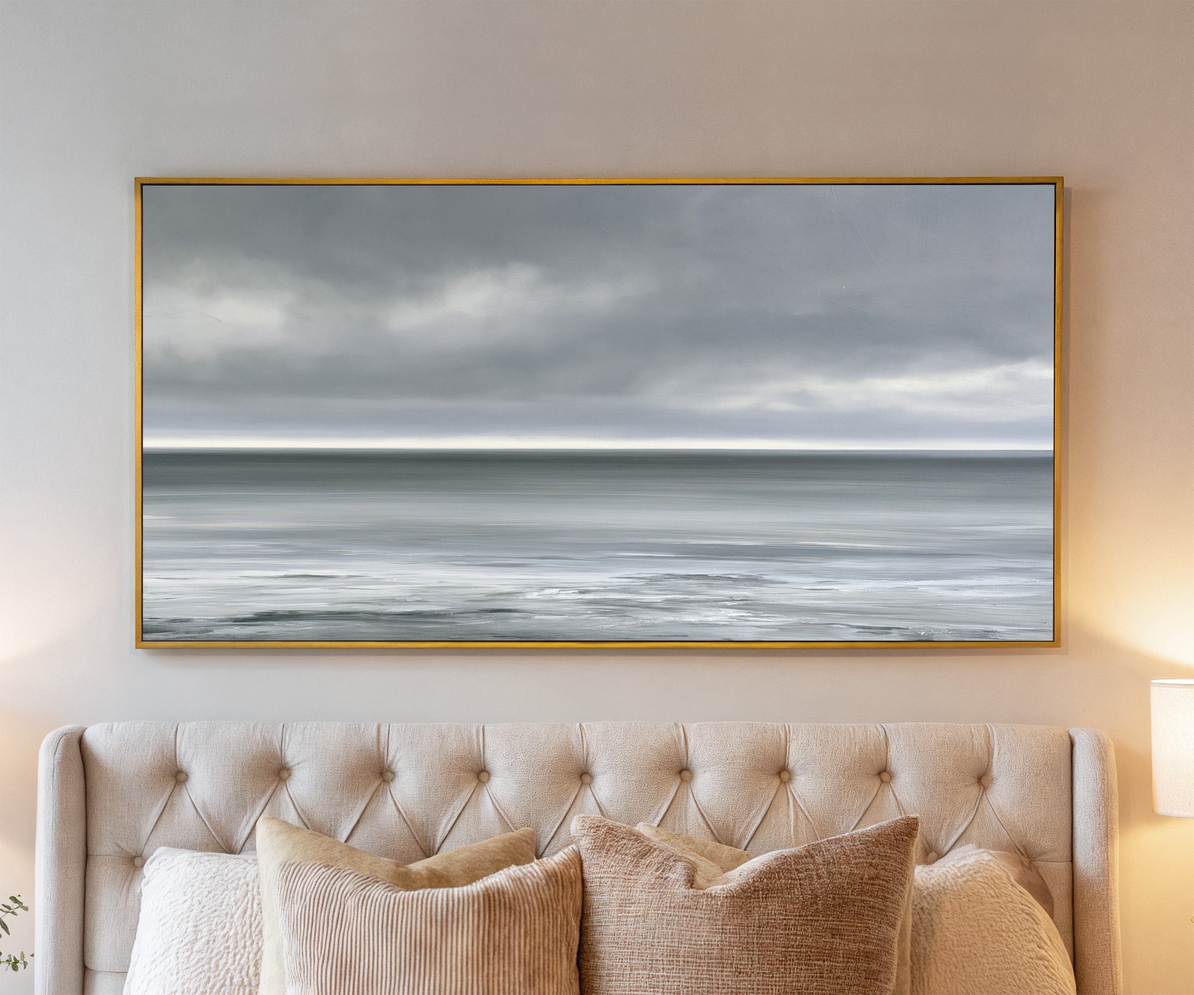 nearly monochrome sea beneath a smoke grey sky canvas wall art in a gold frame above a bed