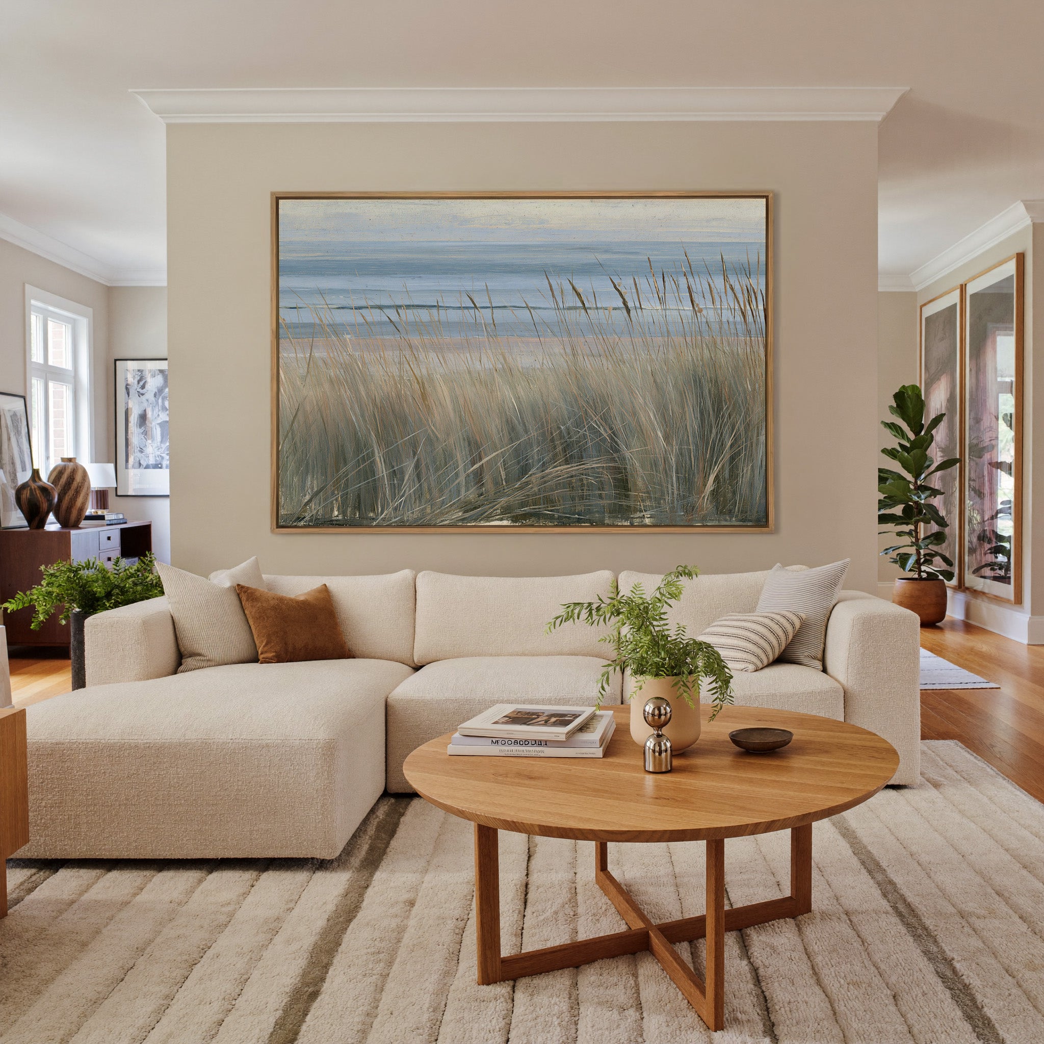 beach grass with blue water and pale dune bands canvas wall art in an oak frame in a living room
