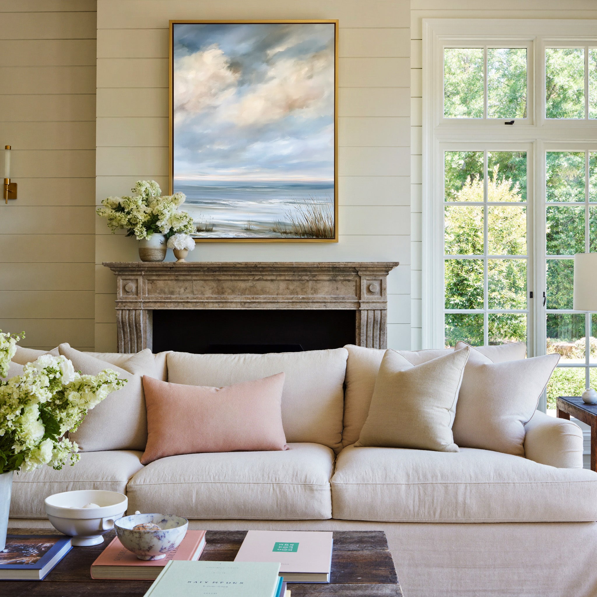 pale coastal horizon beneath broken clouds canvas wall art in a gold frame above a mantel
