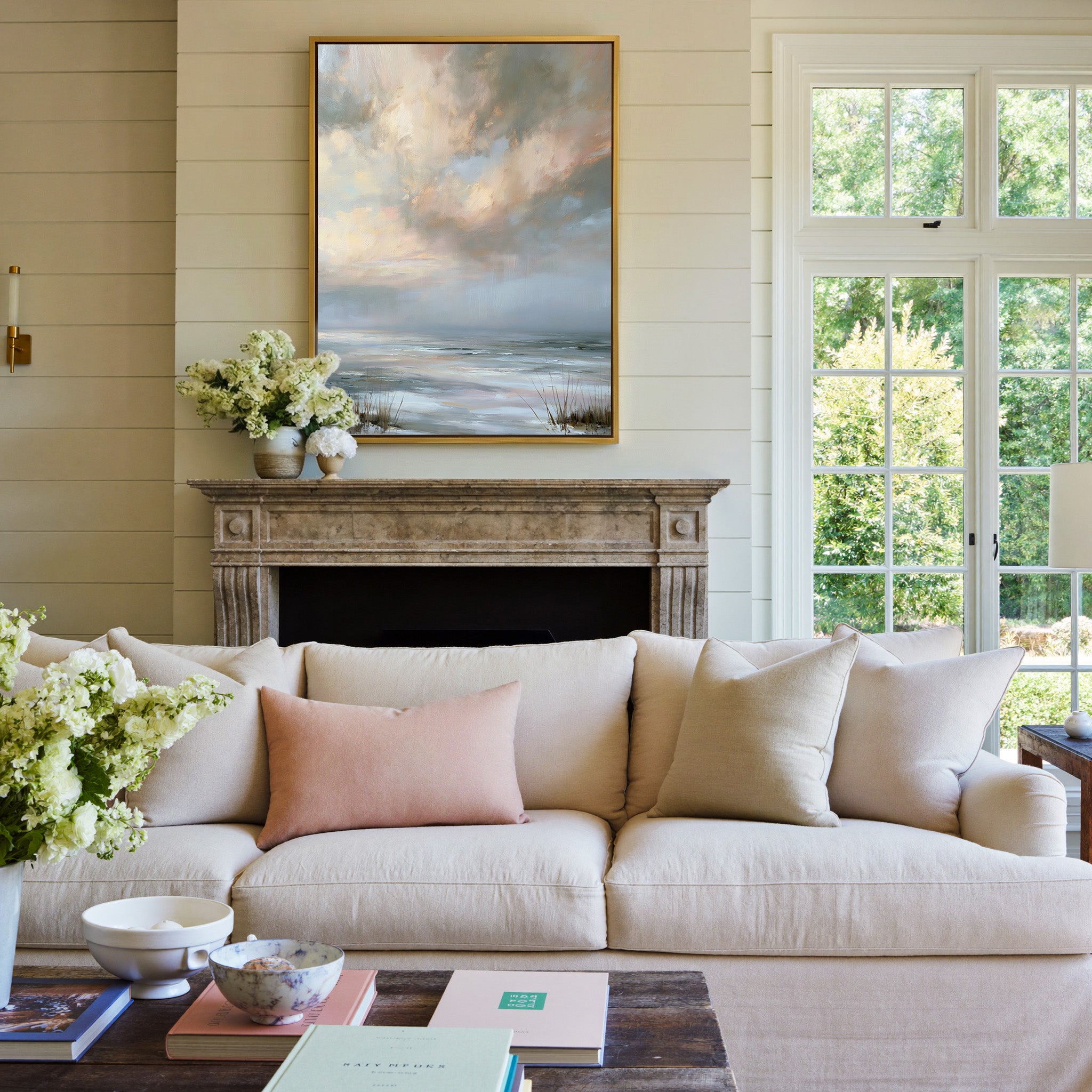 pale coastal horizon beneath broken clouds canvas wall art in a gold frame above a mantel