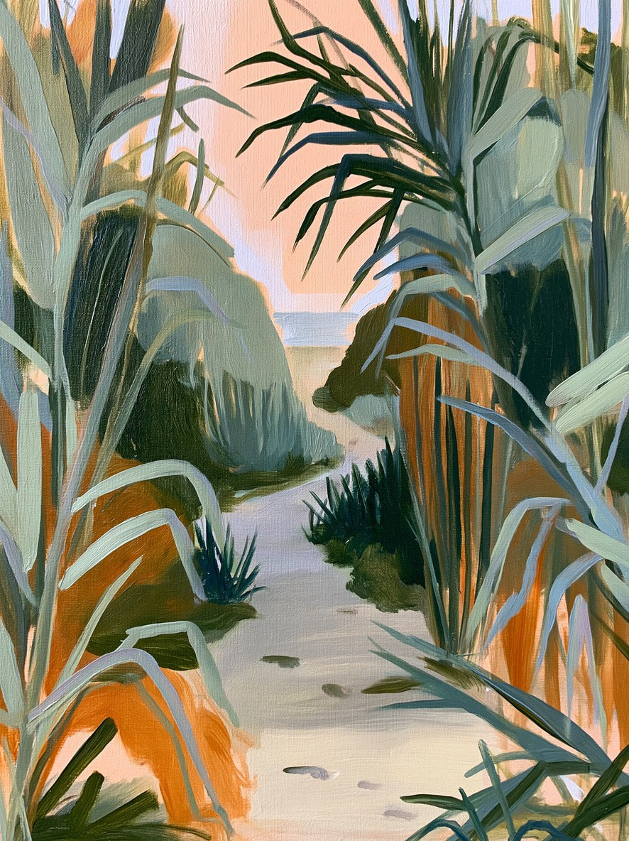 Sandy path between tall coastal grasses, with peach sky and a thin band of water beyond