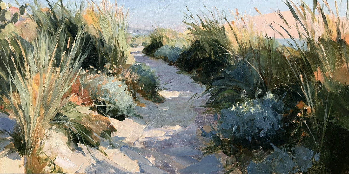 Sandy path between tall coastal grasses with pale blue sky and water beyond