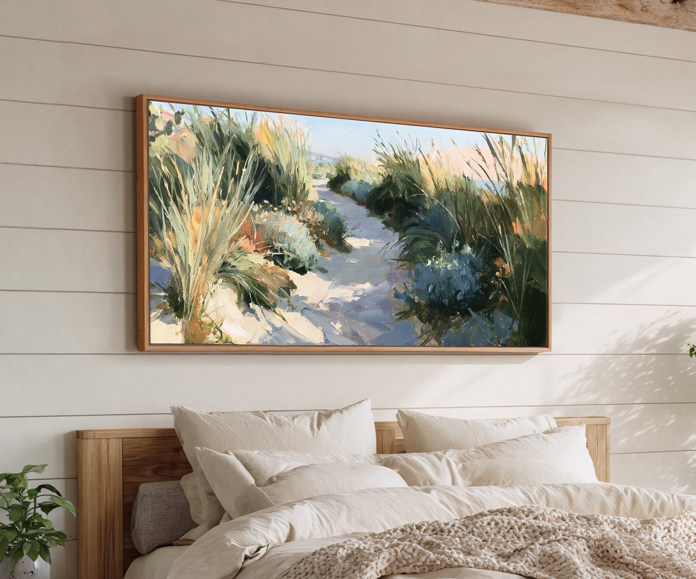 sandy path between tall coastal grasses canvas wall art in an oak frame above a bed