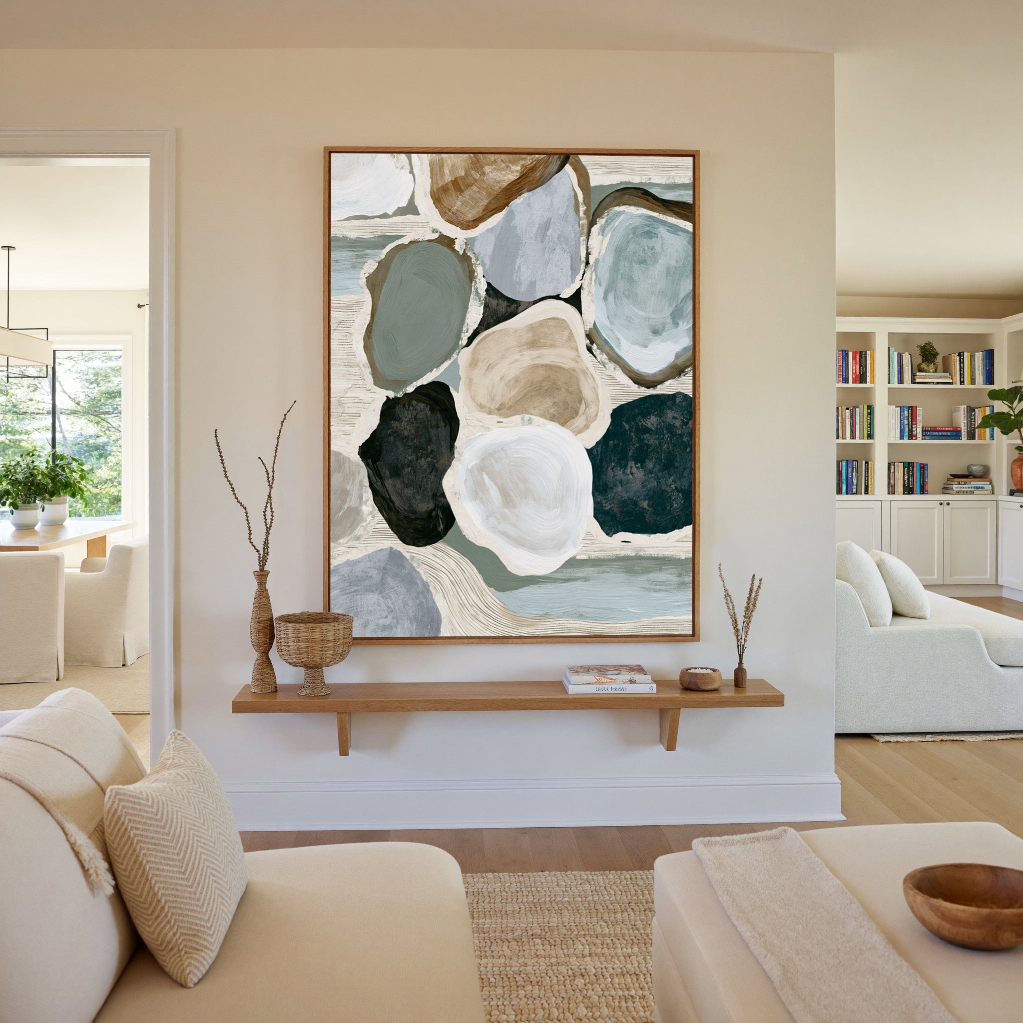 muted coastal abstract with oyster shell shapes canvas wall art in an oak frame in a living room