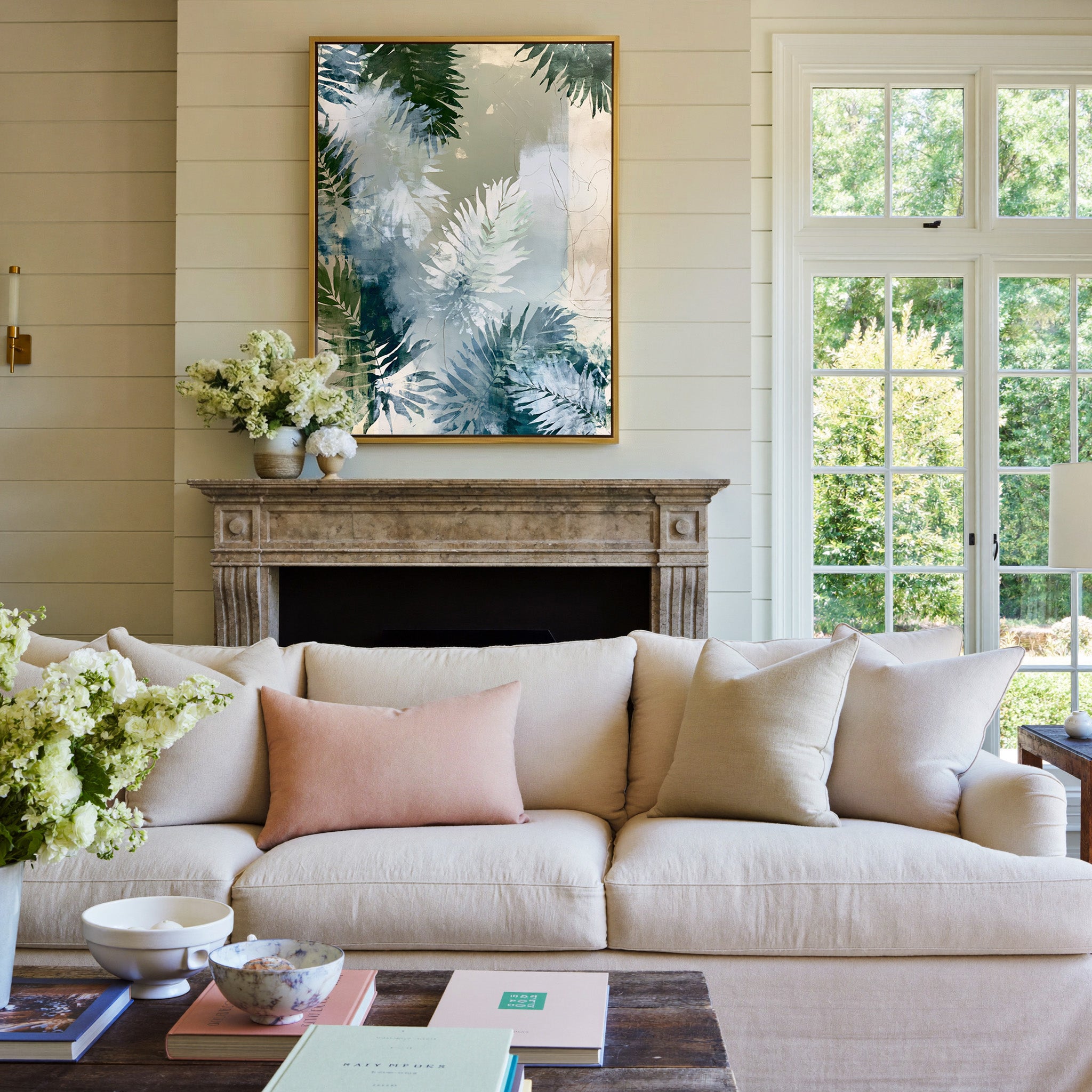 layered fern leaves in sage, blue gray, and canvas wall art in a gold frame above a mantel