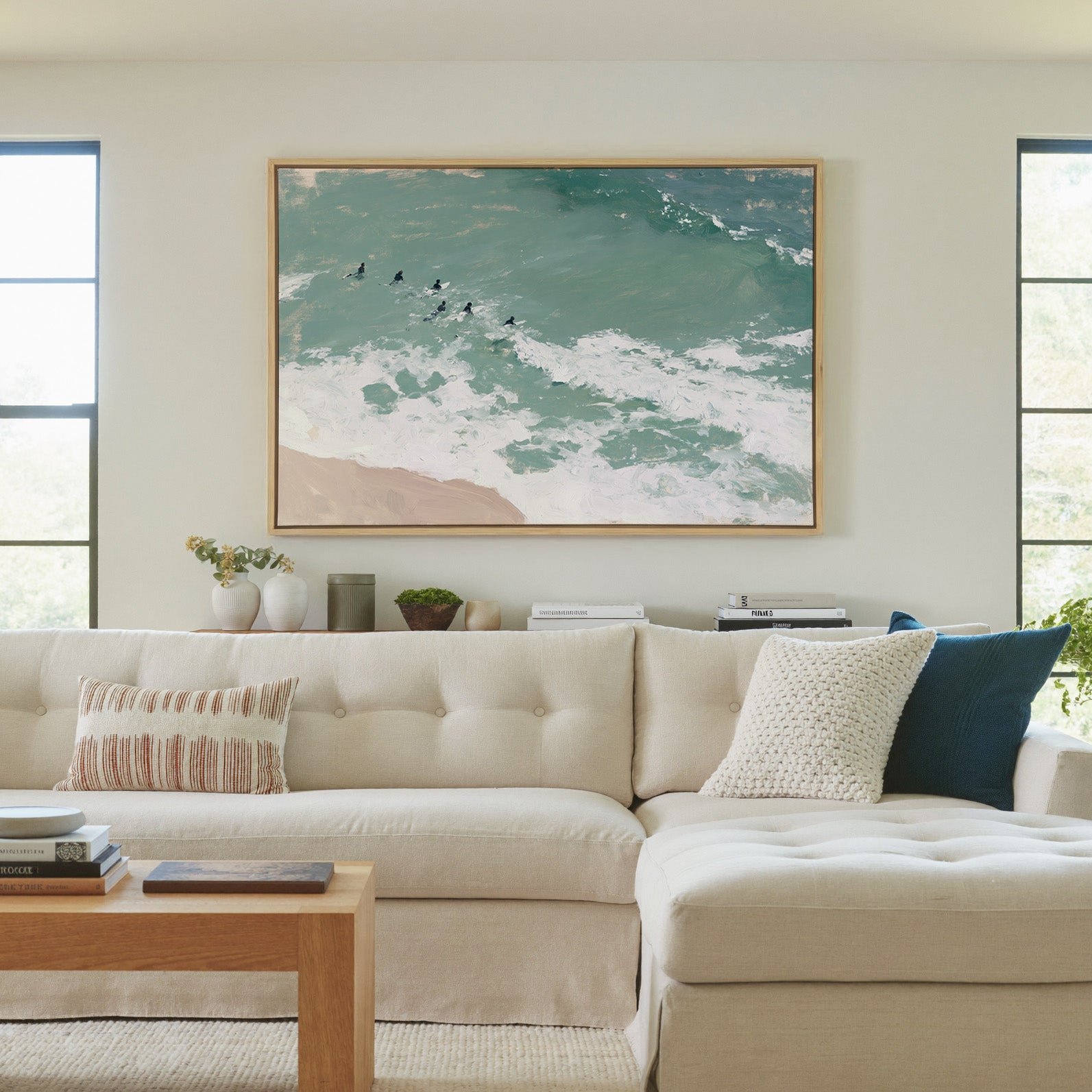 turquoise surf with small figures beyond the canvas wall art in a natural wood frame in a living room