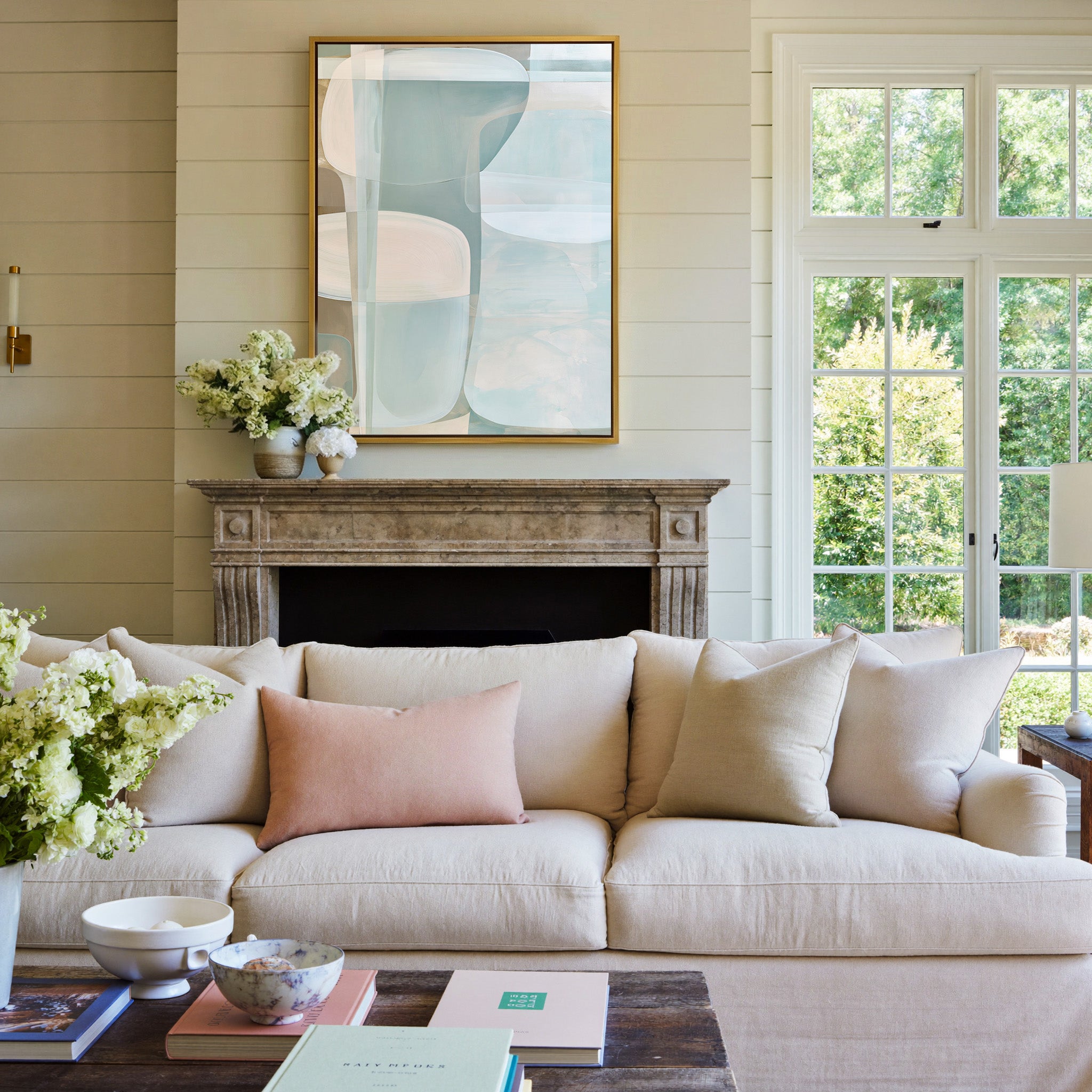 soft blue and beige abstract with rounded canvas wall art in a gold frame above a mantel
