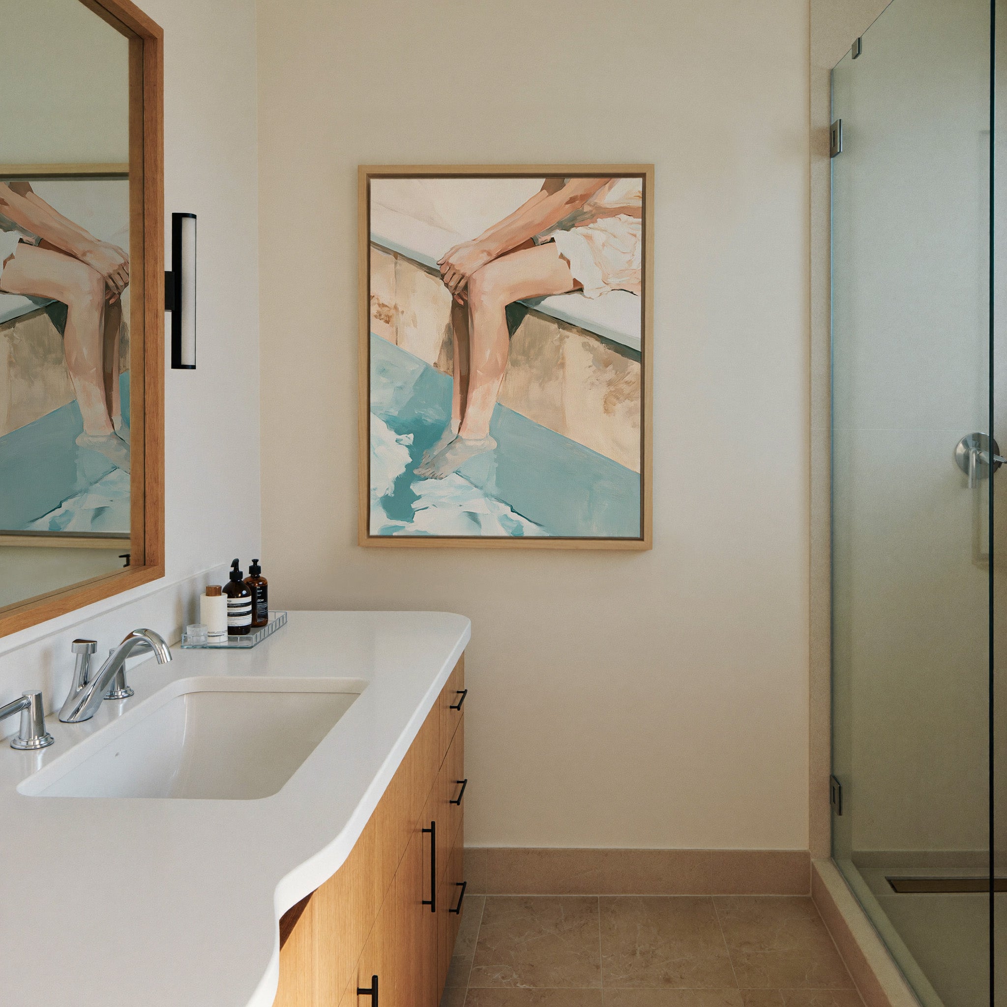 cropped seated figure with bent legs and blue canvas wall art in a natural wood frame in a styled room setting