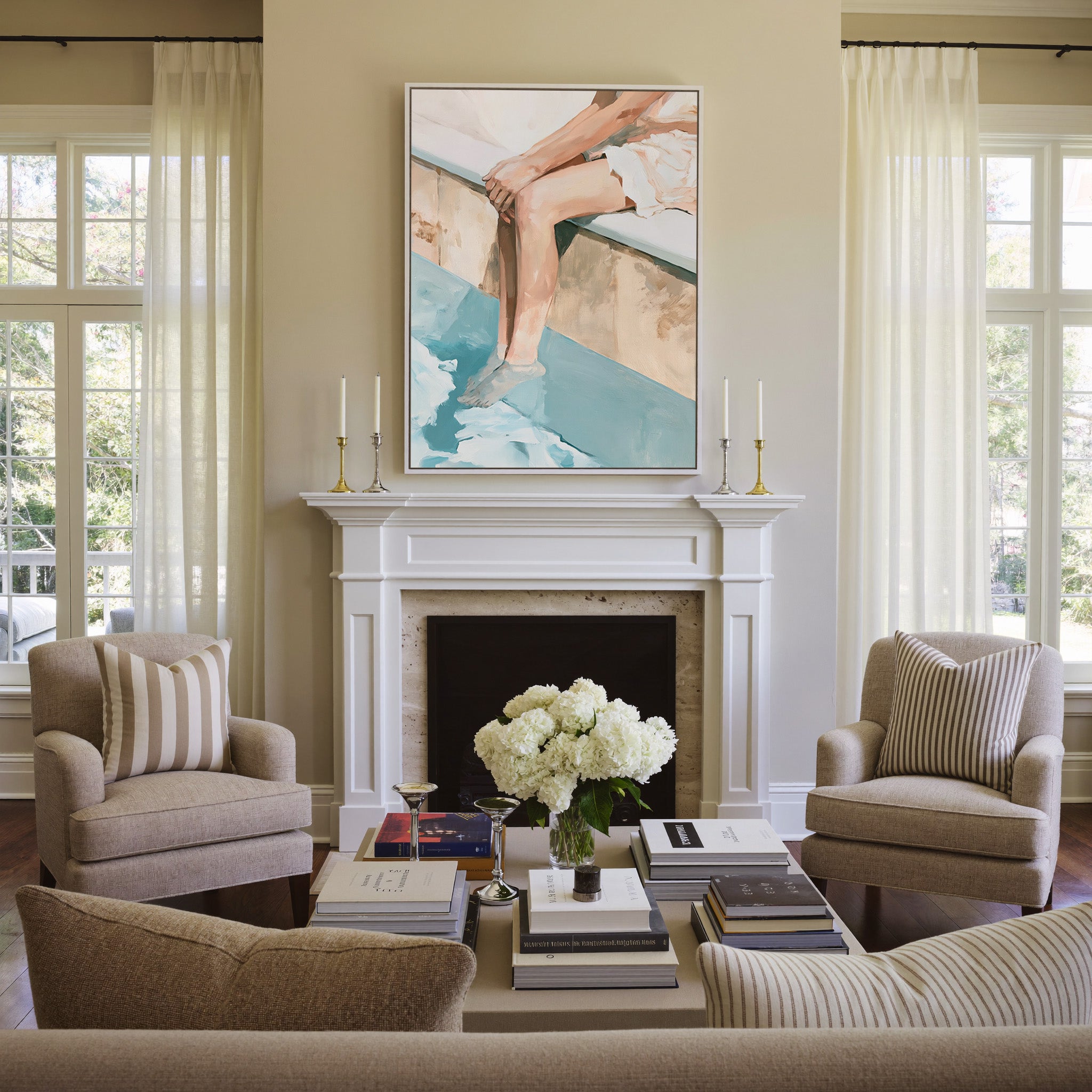 cropped seated figure with bent legs and blue canvas wall art in a white frame above a mantel