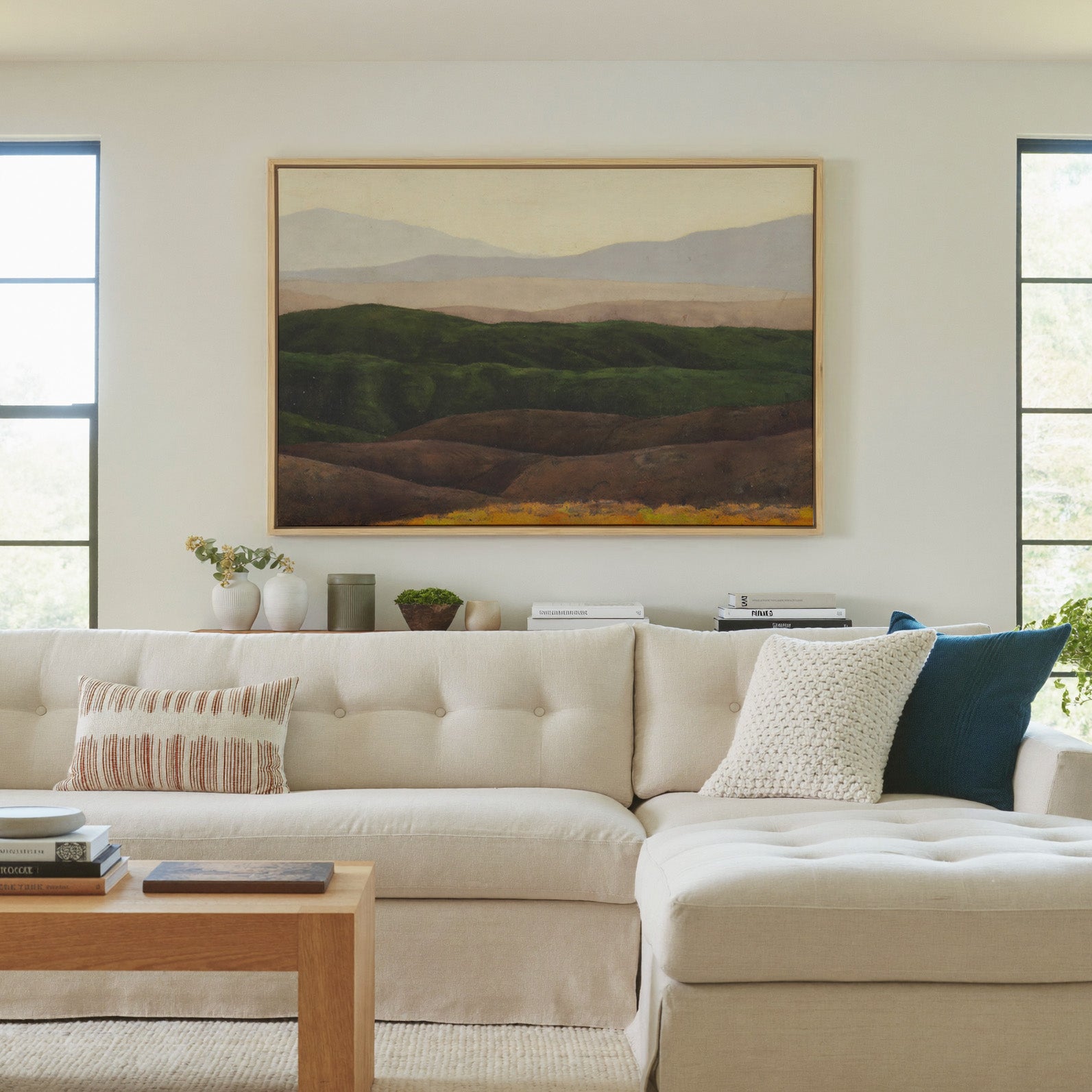 layered green hills with pale distant mountains canvas wall art in a natural wood frame in a living room