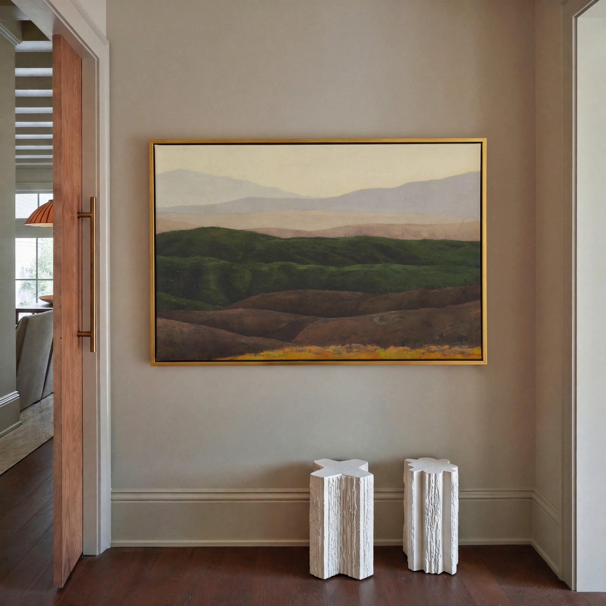 layered green hills with pale distant mountains canvas wall art in a gold frame in a styled room setting