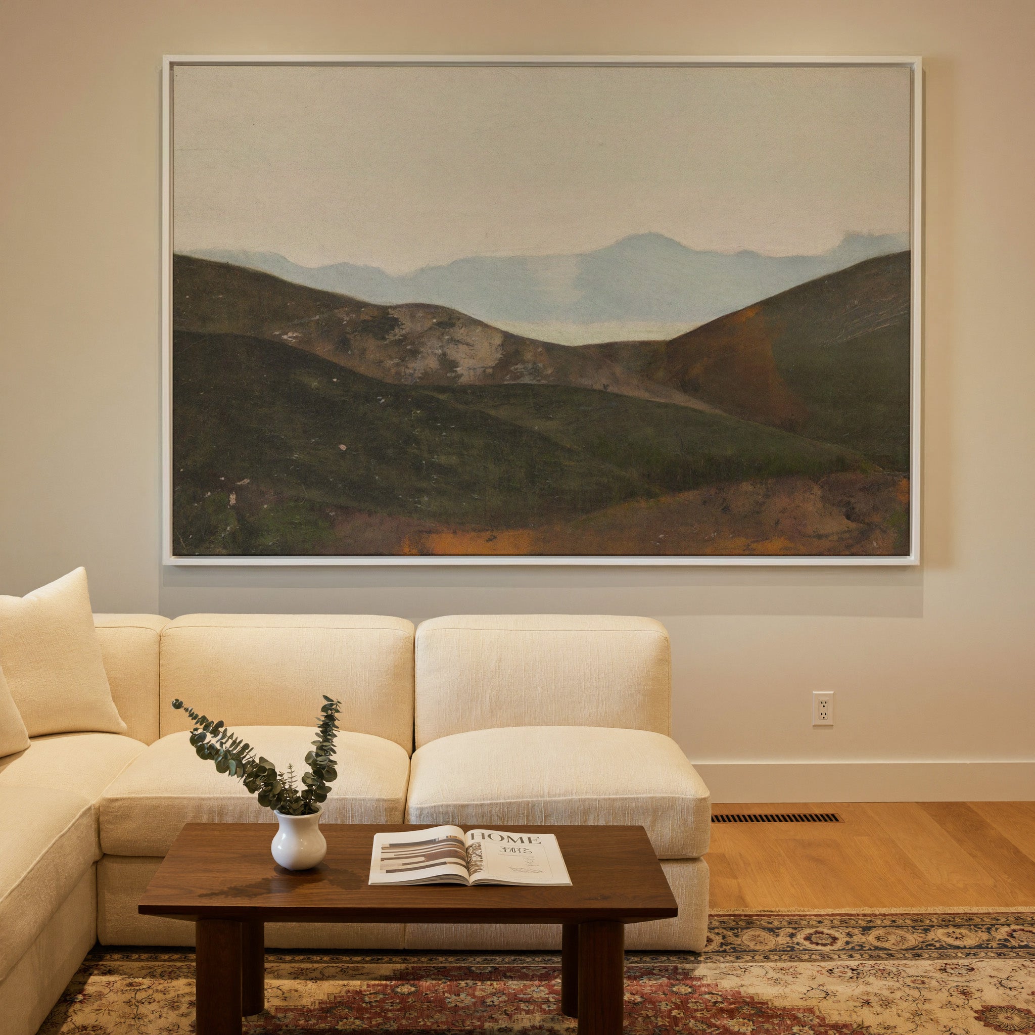 soft blue mountain landscape with dark canvas wall art in a white frame in a styled room setting