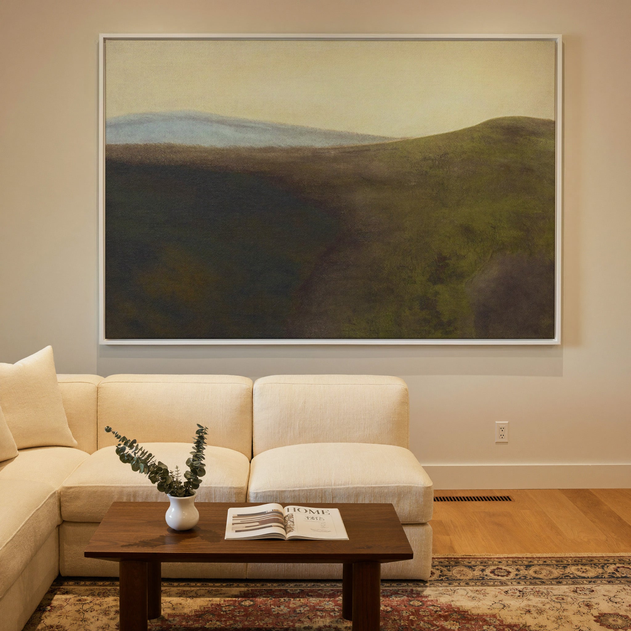 muted green hills with a pale blue ridge and canvas wall art in a white frame in a styled room setting