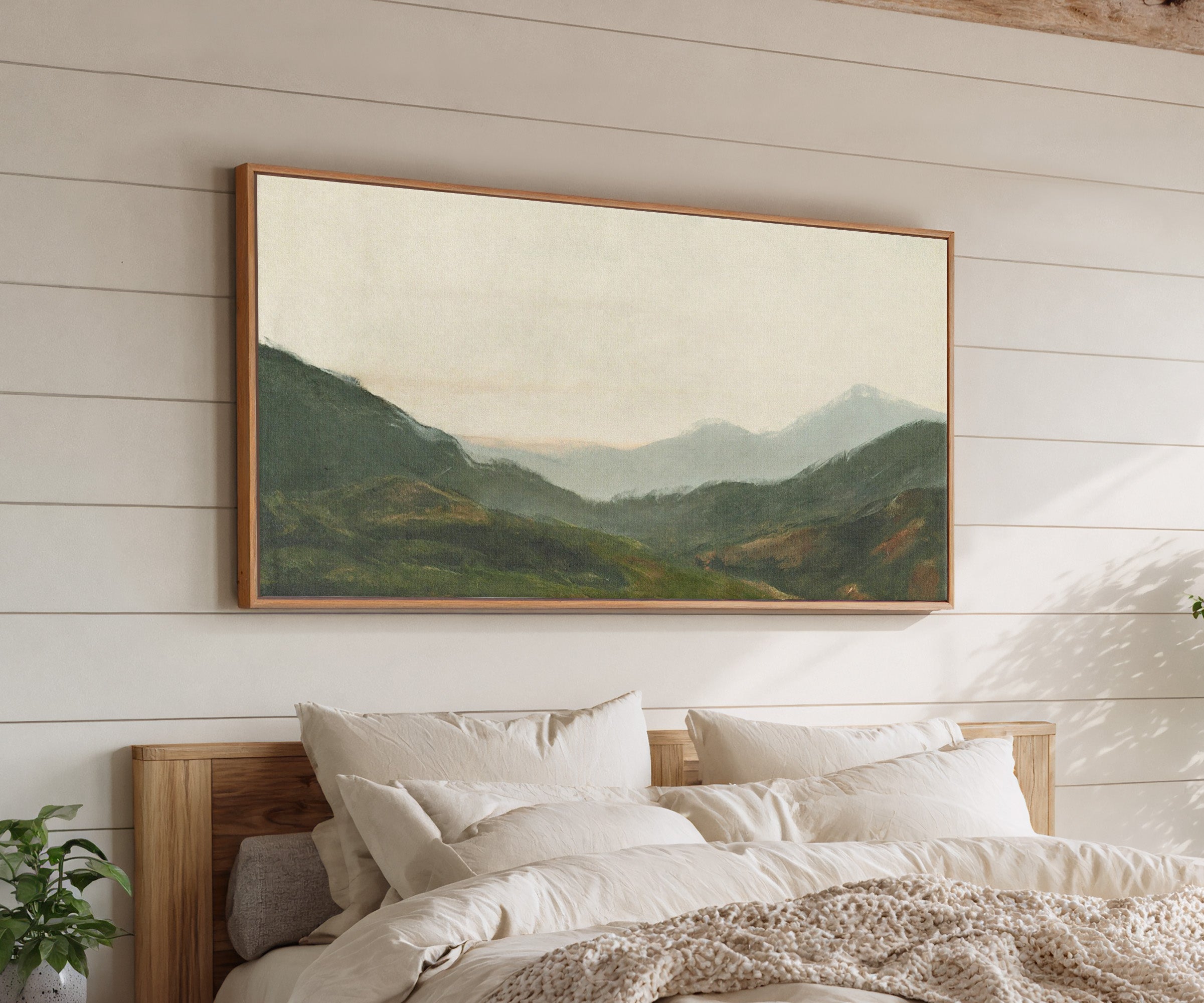 misty green mountain landscape canvas wall art in an oak frame above a bed