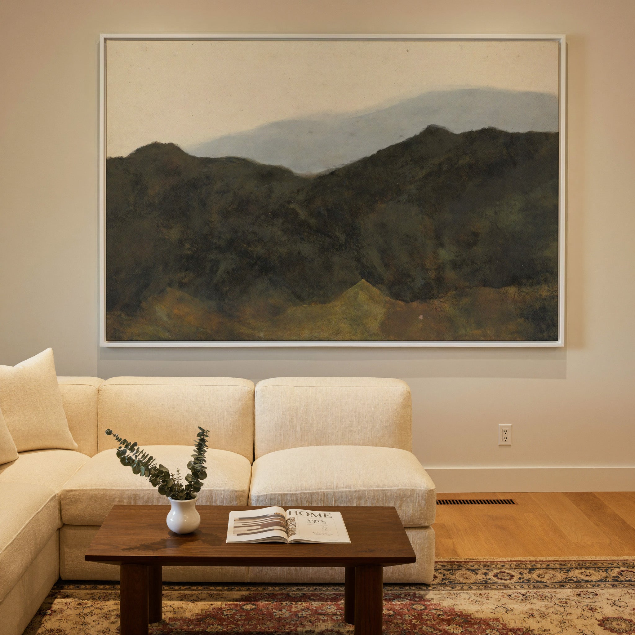 dark mountain ridges beneath a pale hazy sky canvas wall art in a white frame in a styled room setting