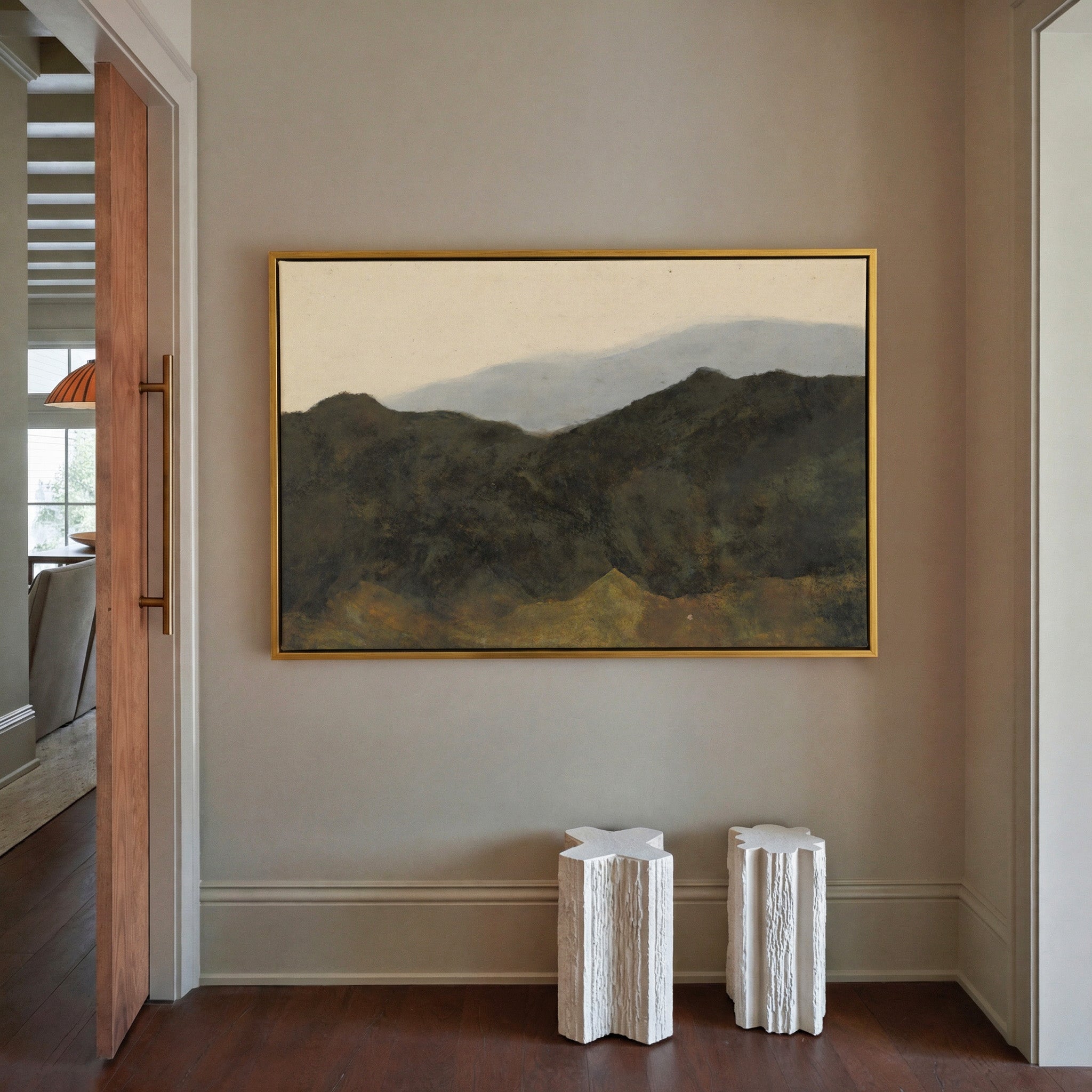dark mountain ridges beneath a pale hazy sky canvas wall art in a gold frame in a styled room setting