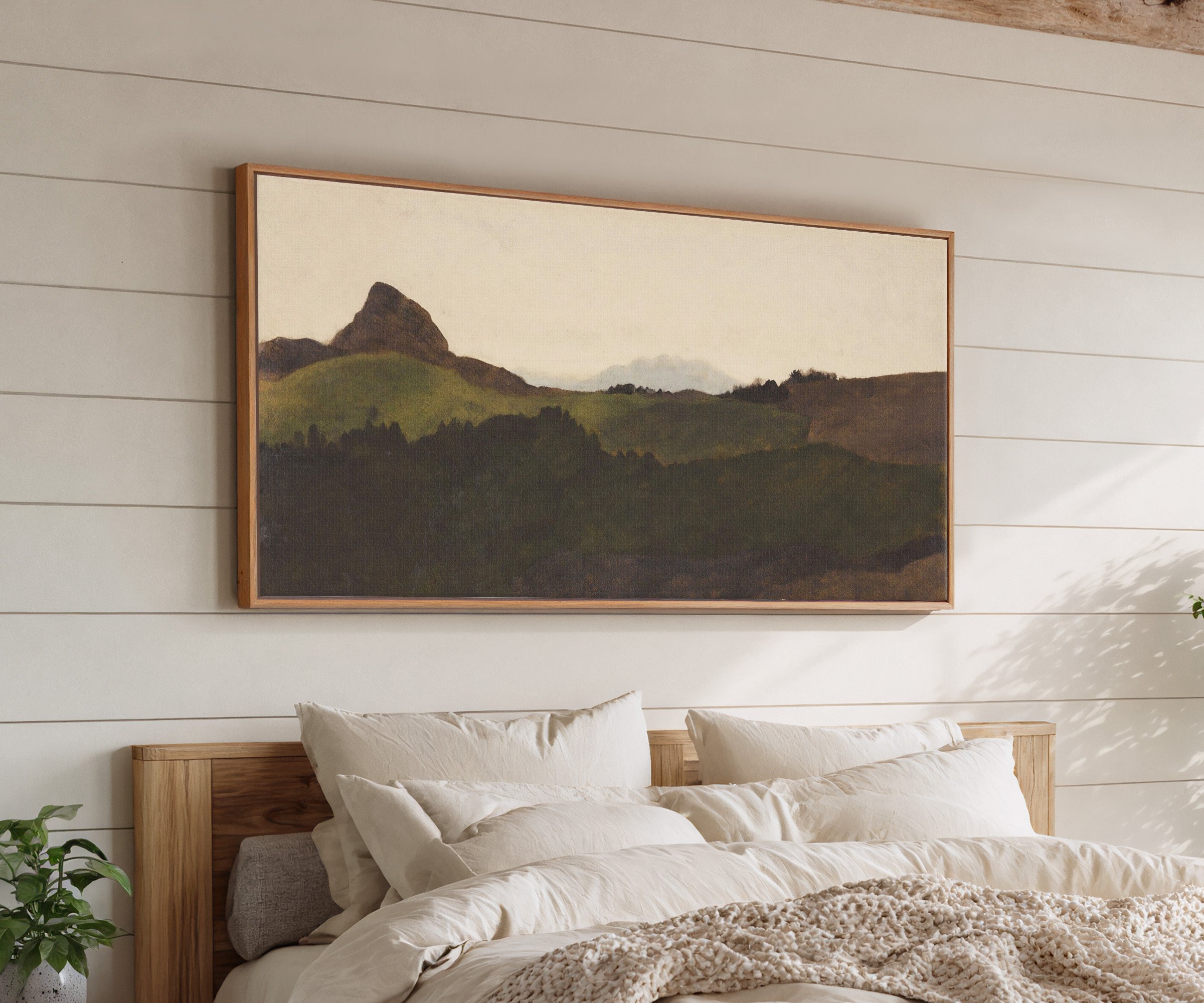 dark green hills with a pale distant peak canvas wall art in an oak frame above a bed