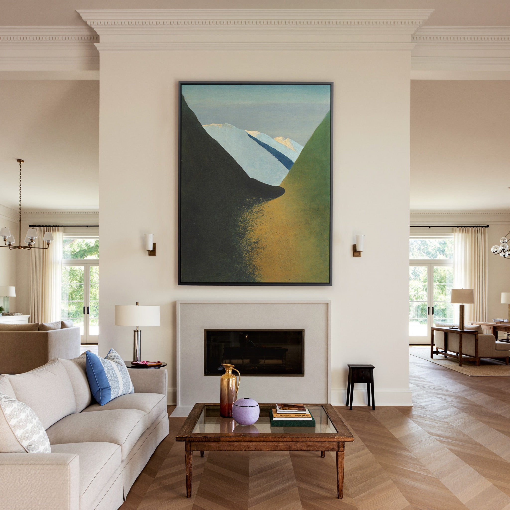 dark foreground slopes with pale blue peaks and canvas wall art in a black frame above a mantel