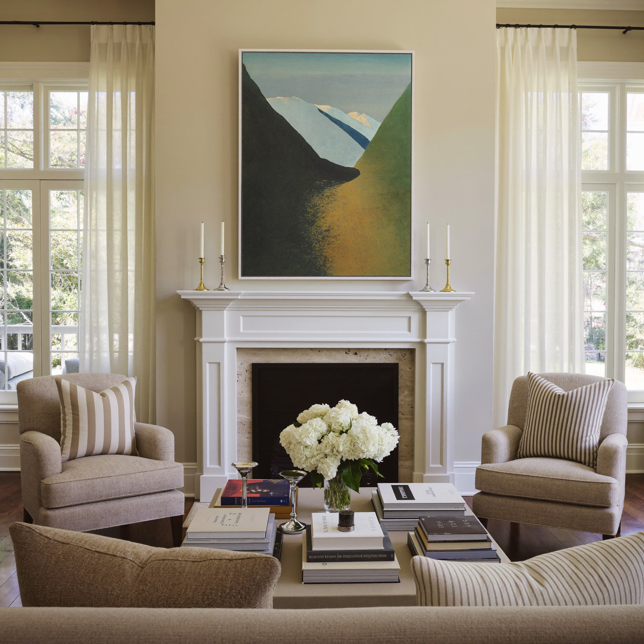 dark foreground slopes with pale blue peaks and canvas wall art in a white frame above a mantel