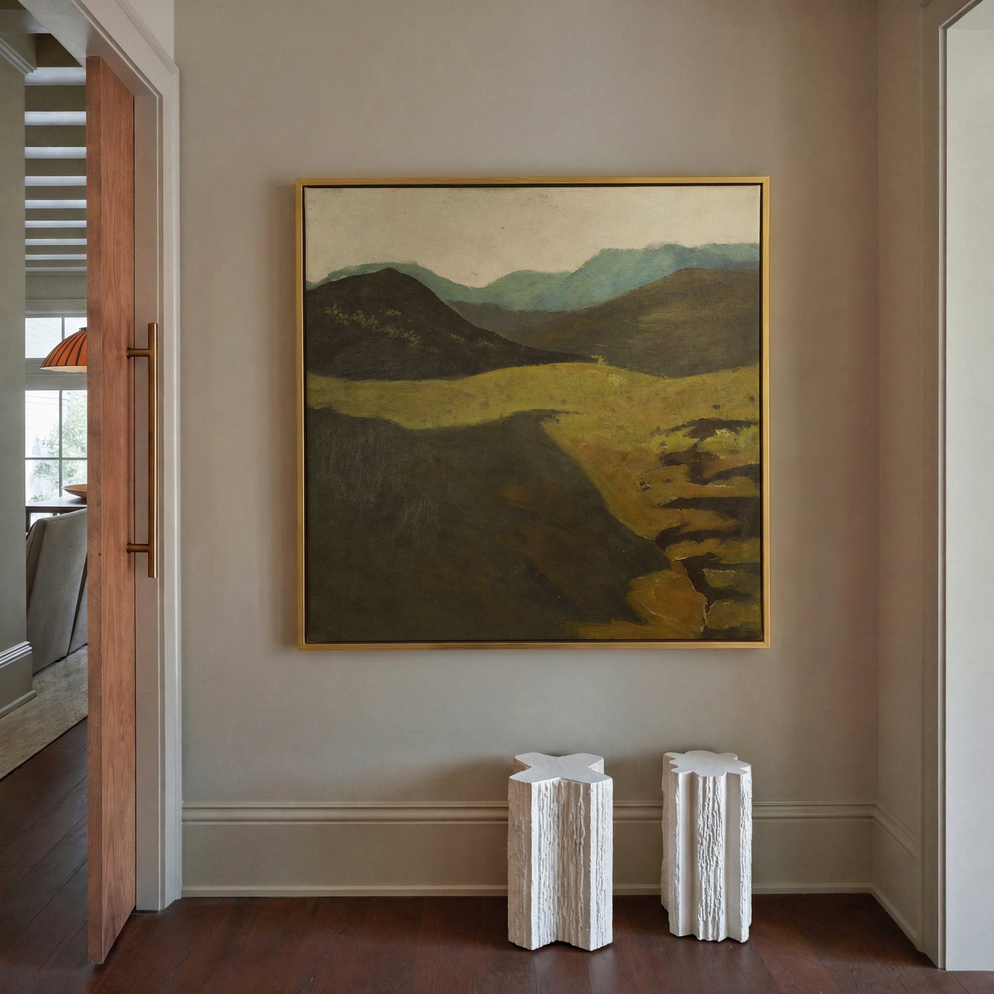 muted mountain landscape with dark foreground canvas wall art in a gold frame in a styled room setting