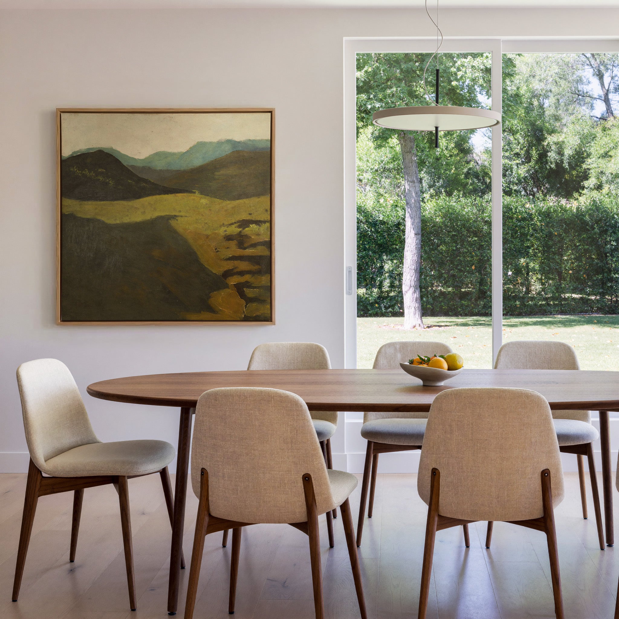 muted mountain landscape with dark foreground canvas wall art in an oak frame in a dining room