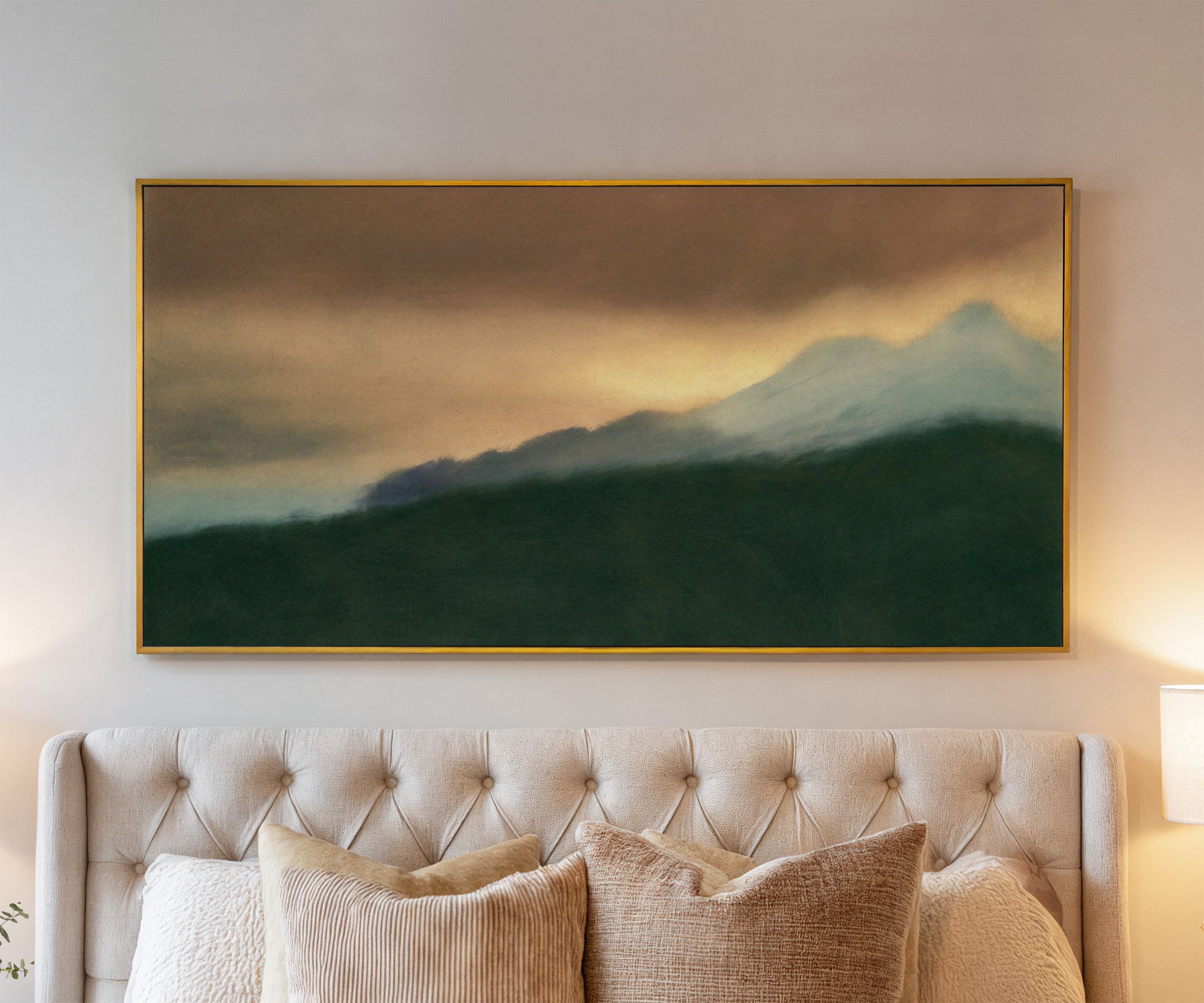 dark green foreground with pale blue peaks and canvas wall art in a gold frame above a bed