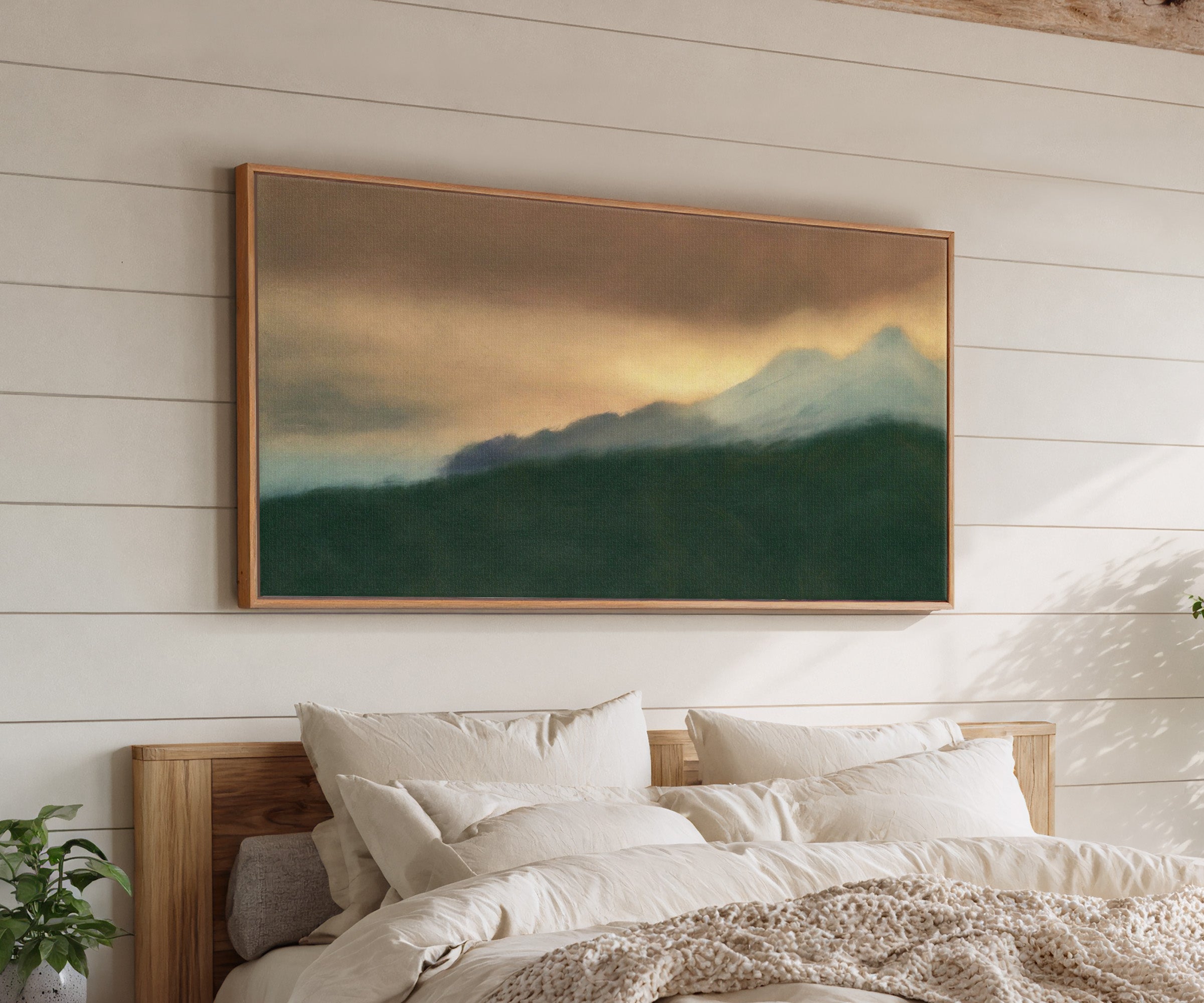 dark green foreground with pale blue peaks and canvas wall art in an oak frame above a bed