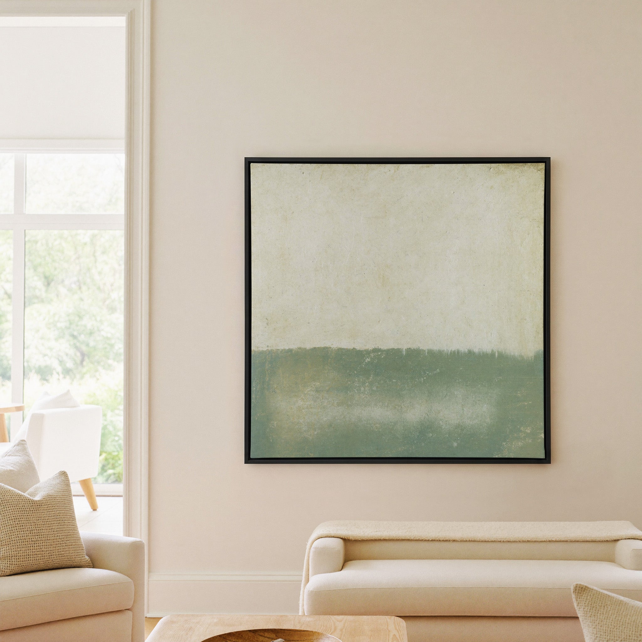 soft sage and cream abstract with a low canvas wall art in a black frame in a living room