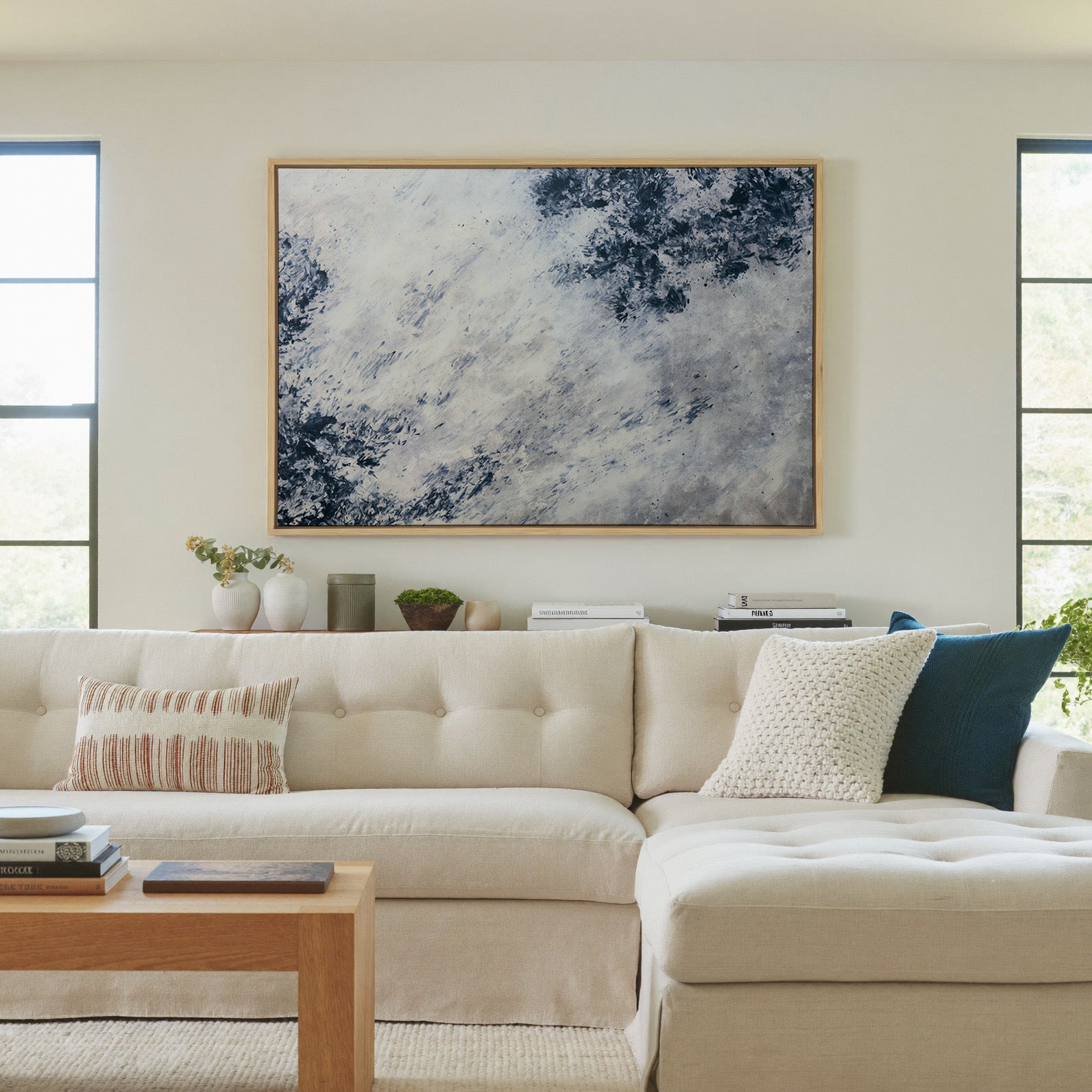 soft black and blue abstract with scattered canvas wall art in a natural wood frame in a living room