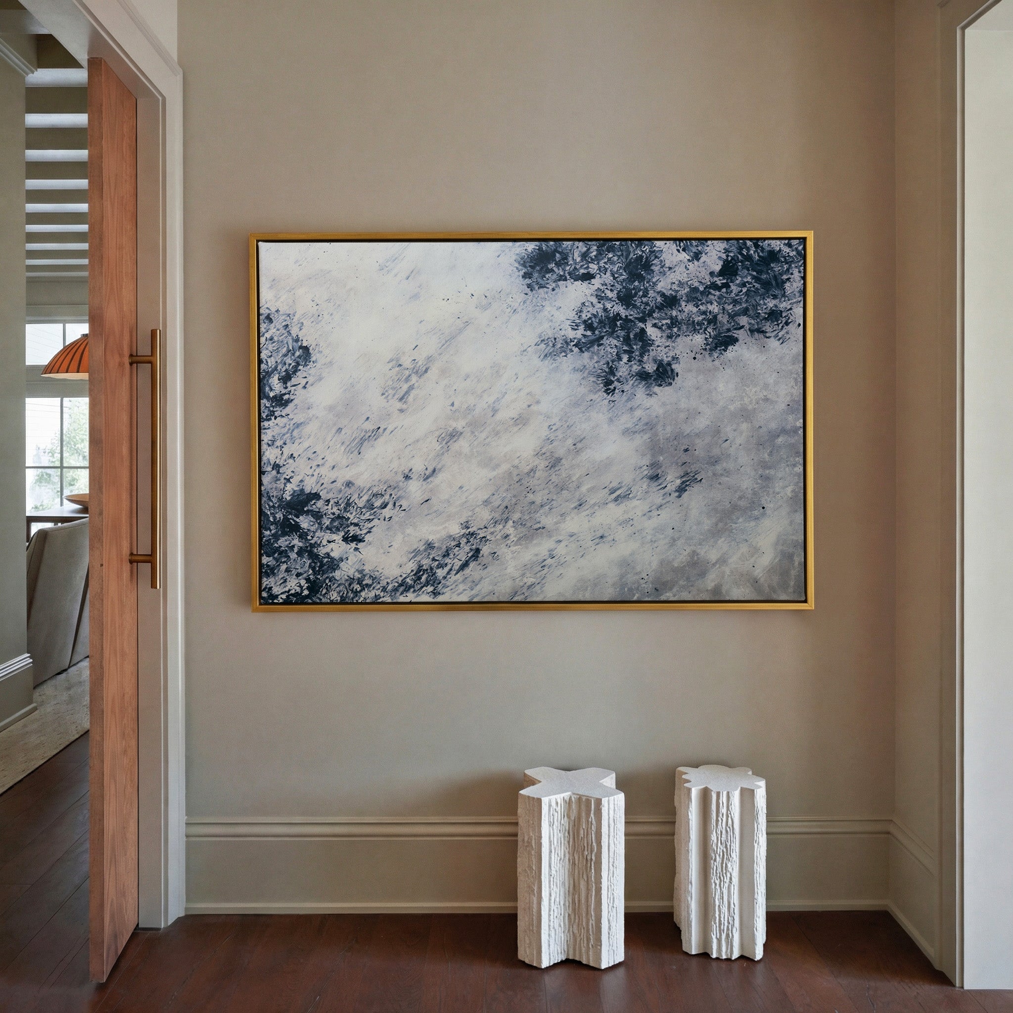 soft black and blue abstract with scattered canvas wall art in a gold frame in a styled room setting