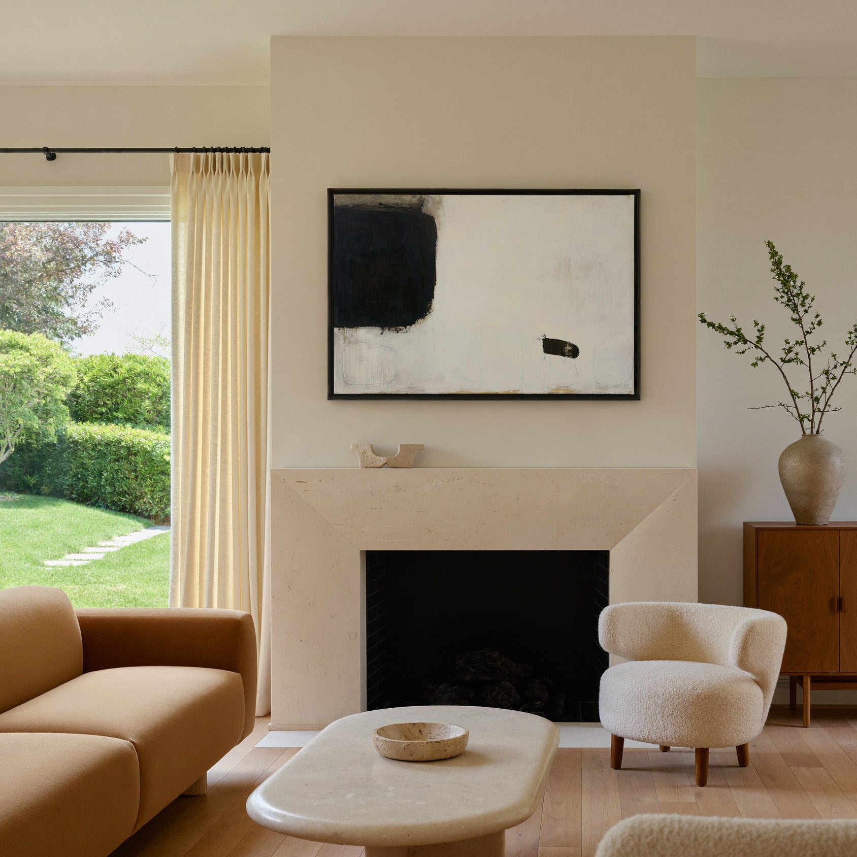 sparse black and cream abstract with heavy dark canvas wall art in a black frame above a mantel
