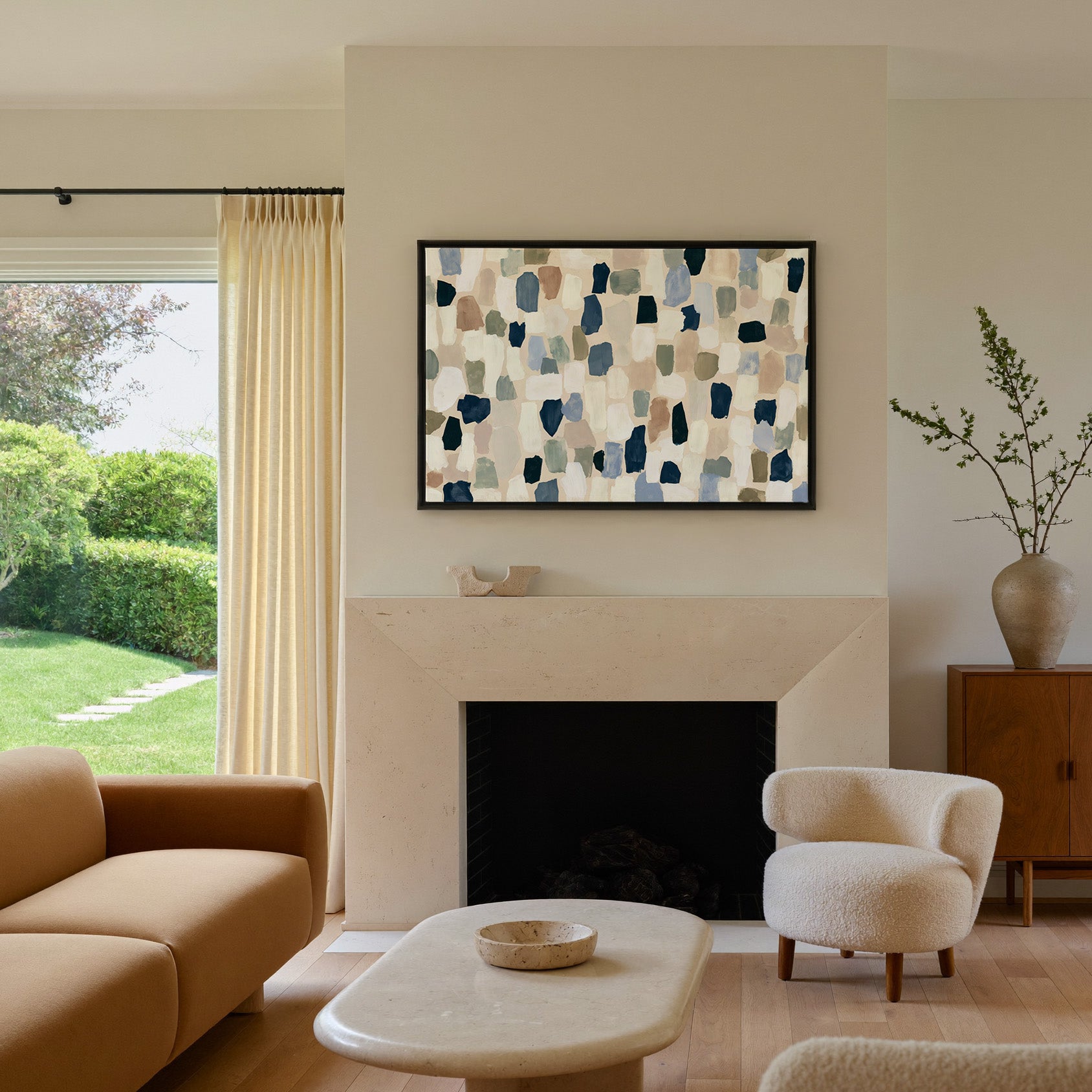 warm stone abstract with drifting hand cut canvas wall art in a black frame above a mantel