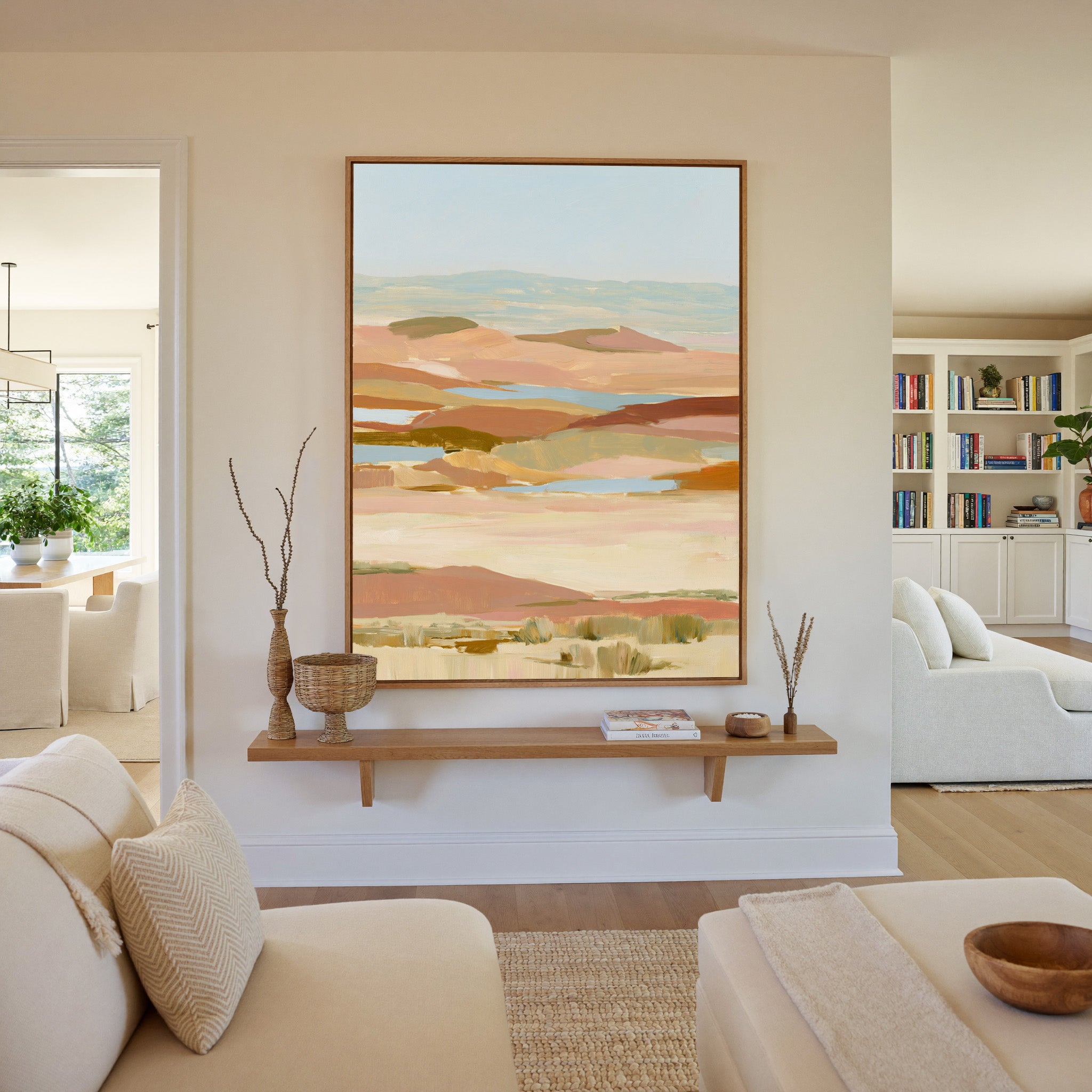 soft desert hills in blush, sand, blue, and canvas wall art in an oak frame in a living room
