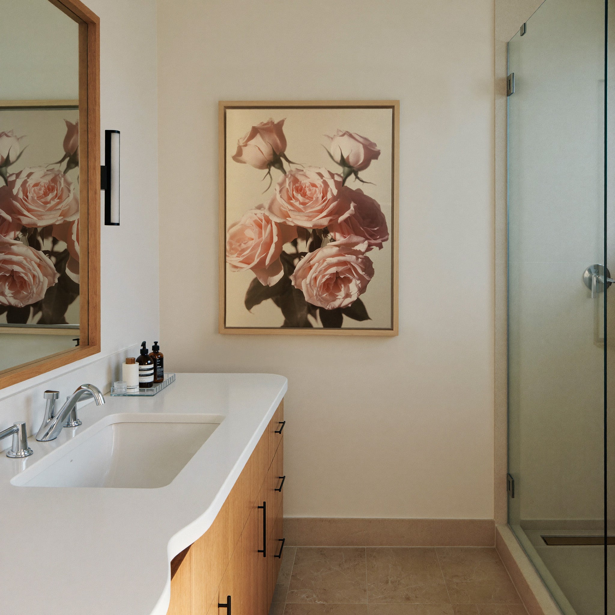 soft pink roses with dark leaves on a pale canvas wall art in a natural wood frame in a styled room setting