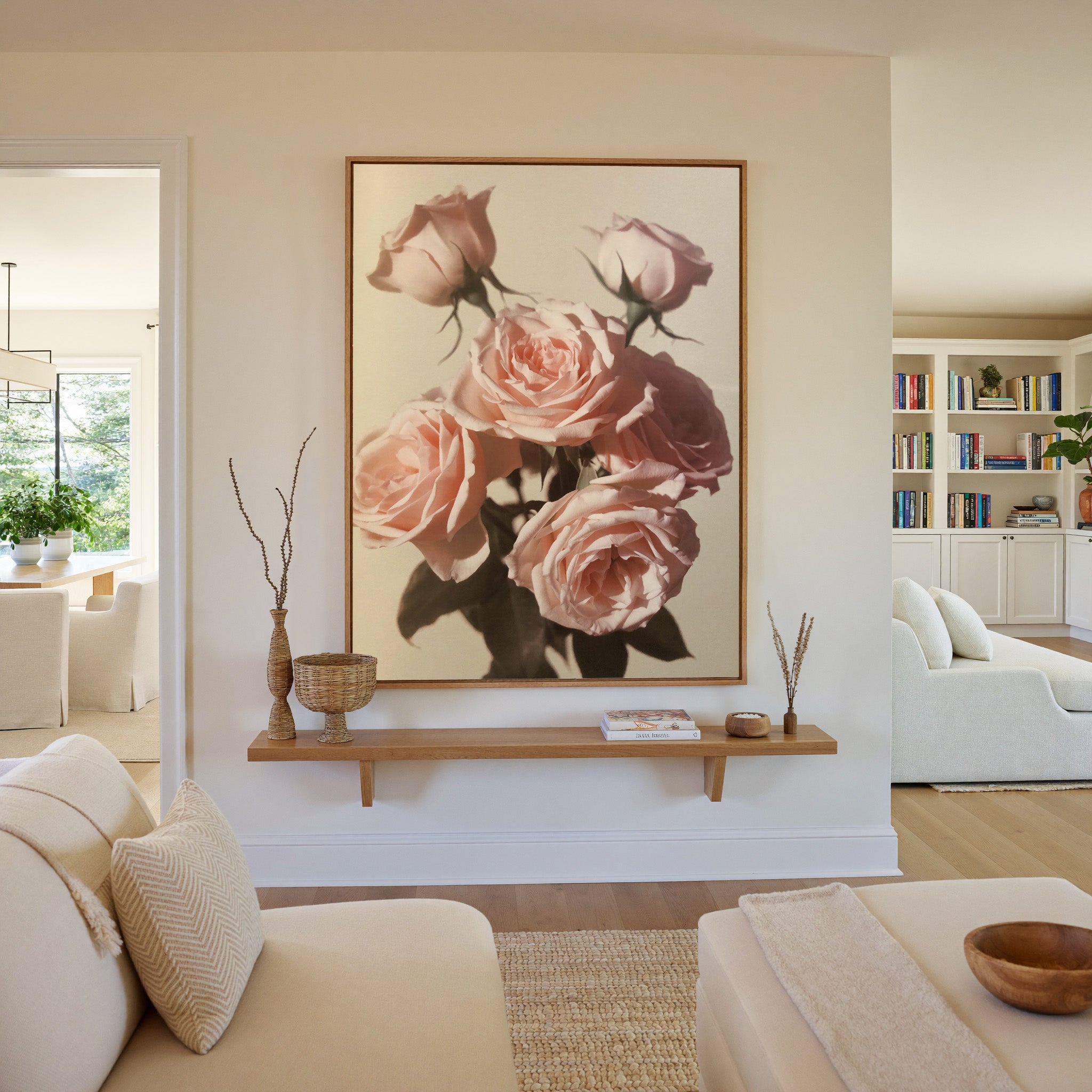 soft pink roses with dark leaves on a pale canvas wall art in an oak frame in a living room