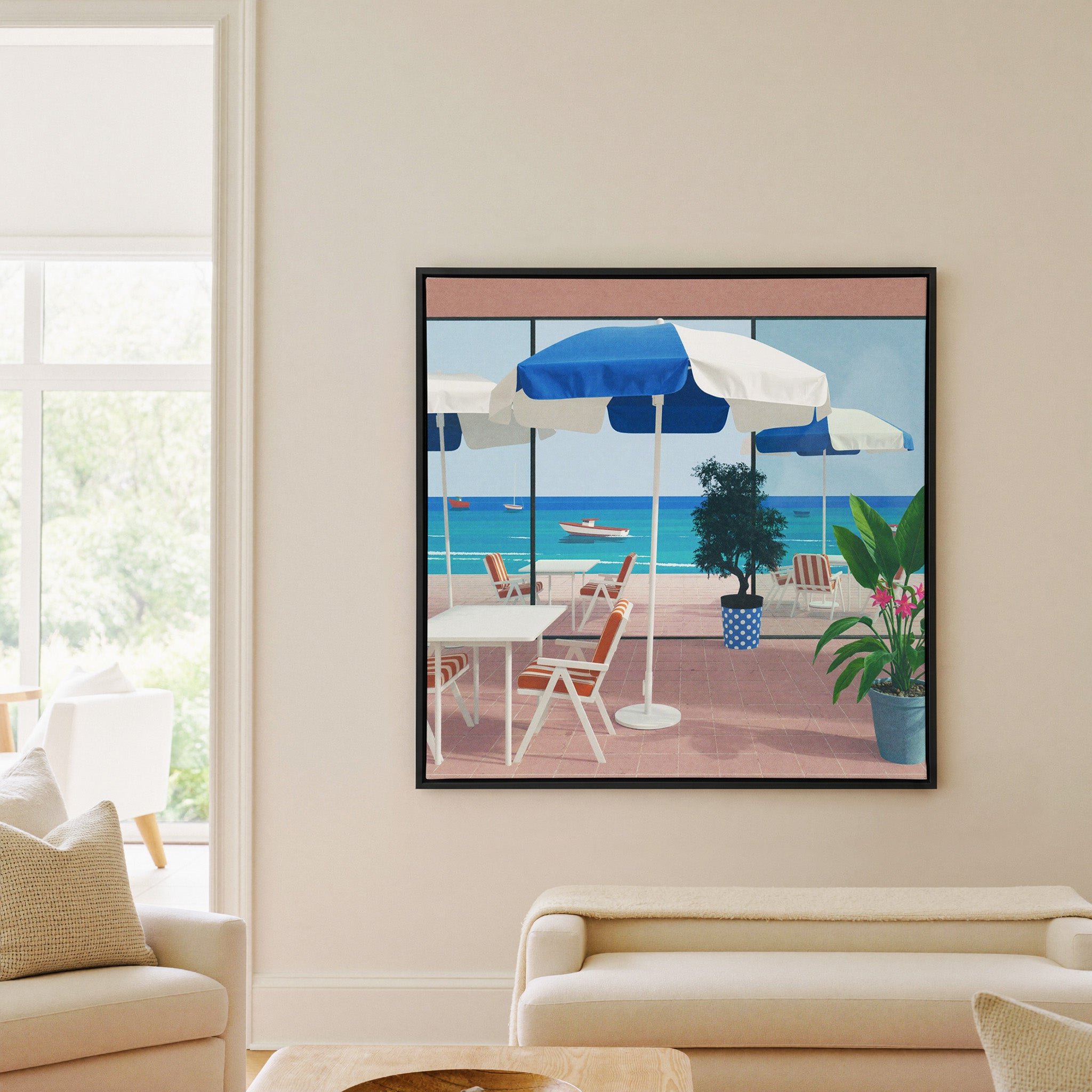 blue umbrellas and striped chairs by the sea canvas wall art in a black frame in a living room
