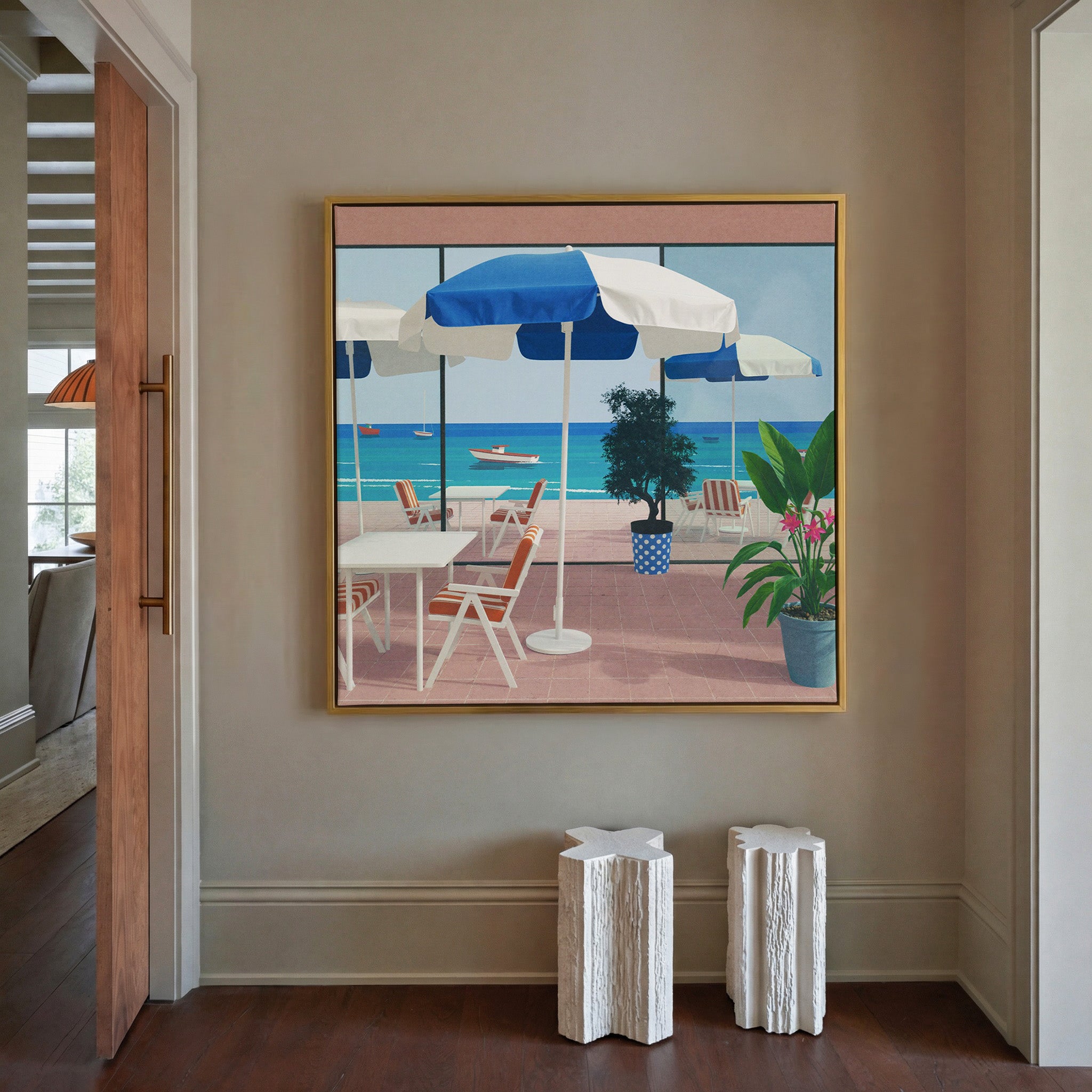 blue umbrellas and striped chairs by the sea canvas wall art in a gold frame in a styled room setting
