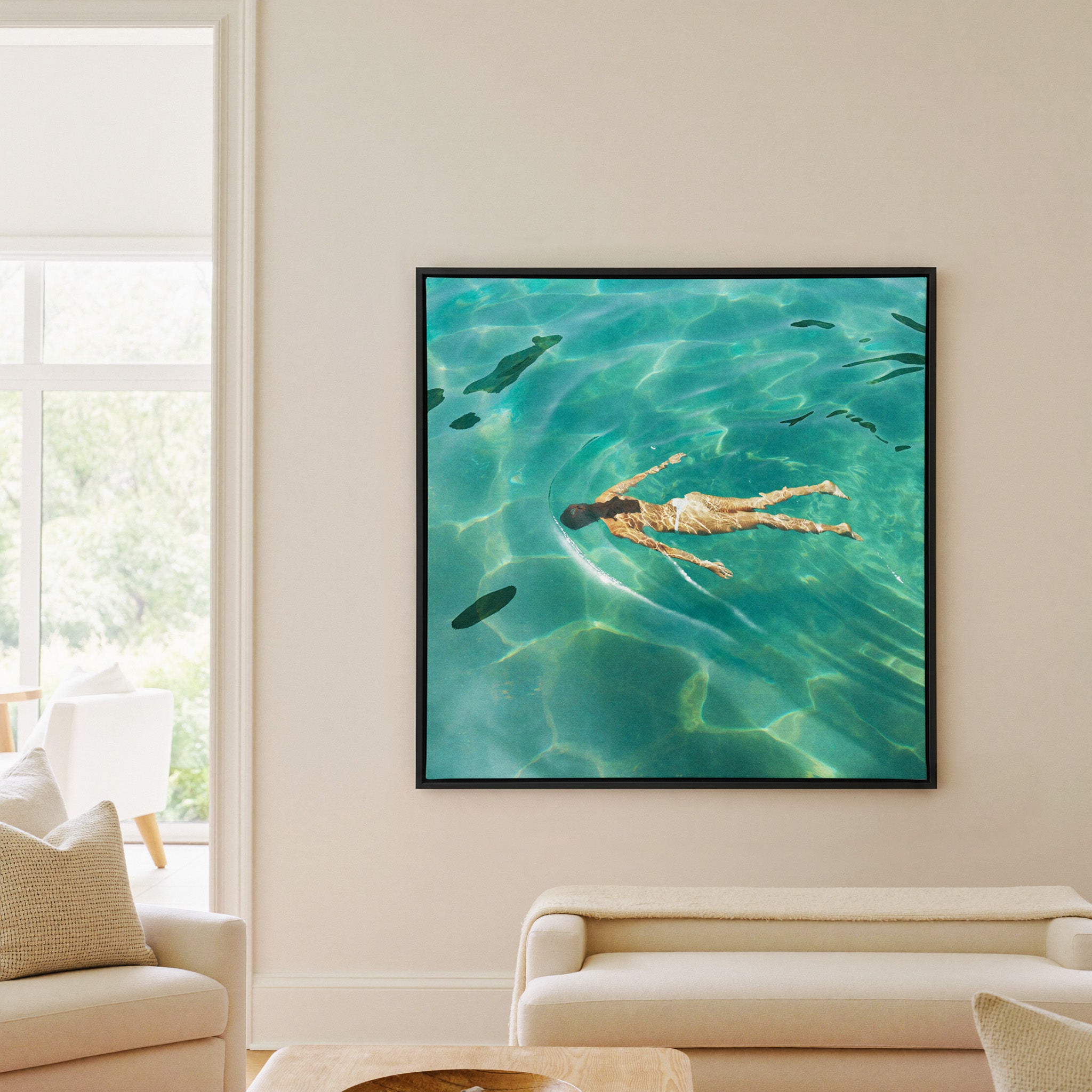 overhead swimmer in turquoise water canvas wall art in a black frame in a living room