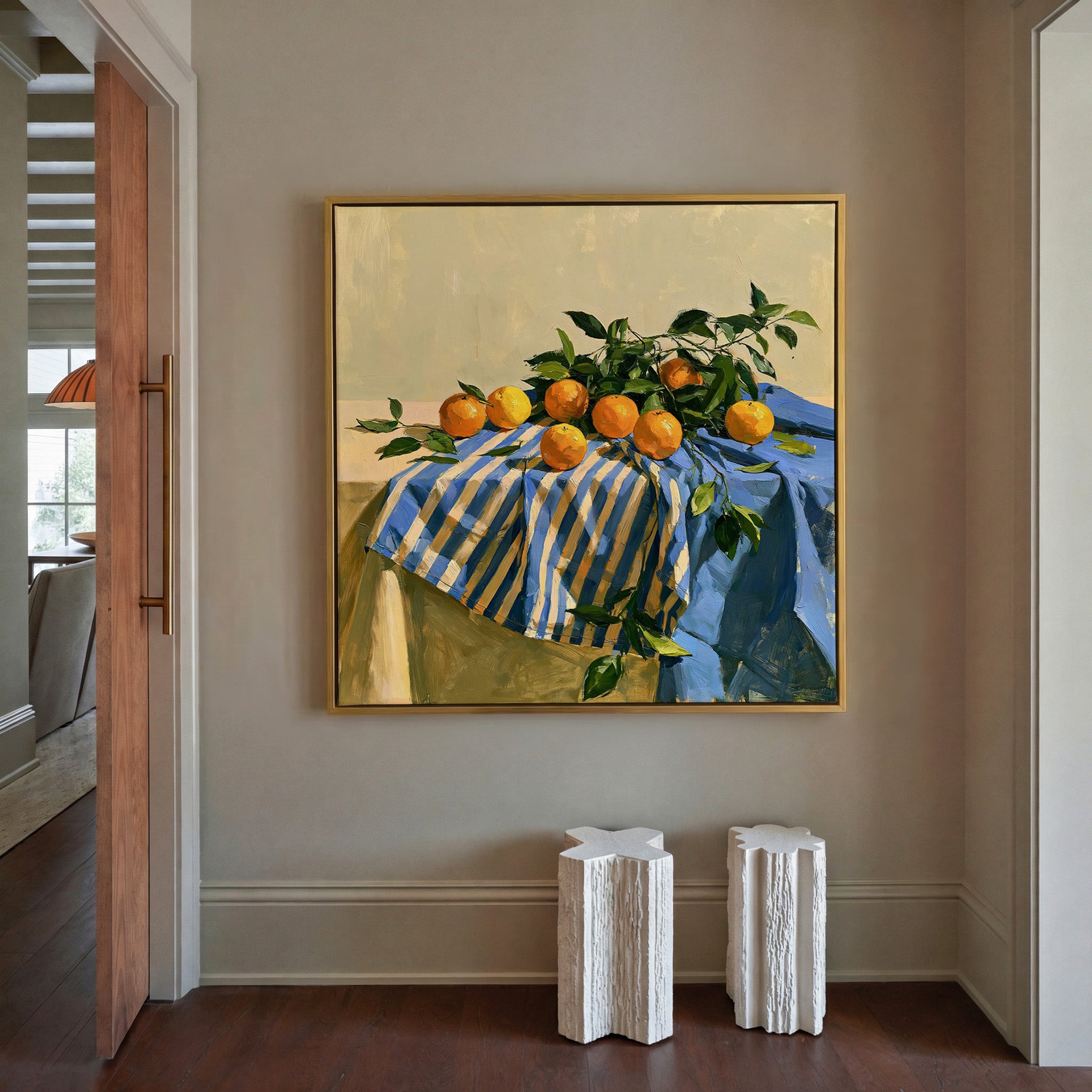 oranges on a blue striped cloth canvas wall art in a gold frame in a styled room setting