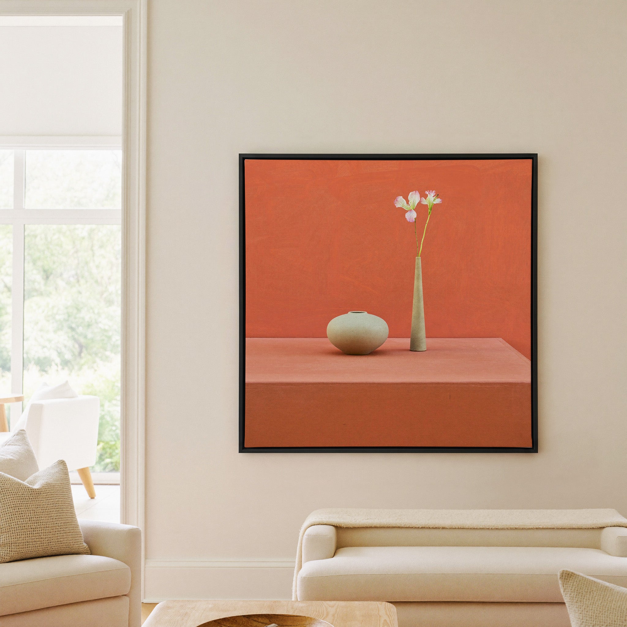 terracotta still life with vase and single stem canvas wall art in a black frame in a living room
